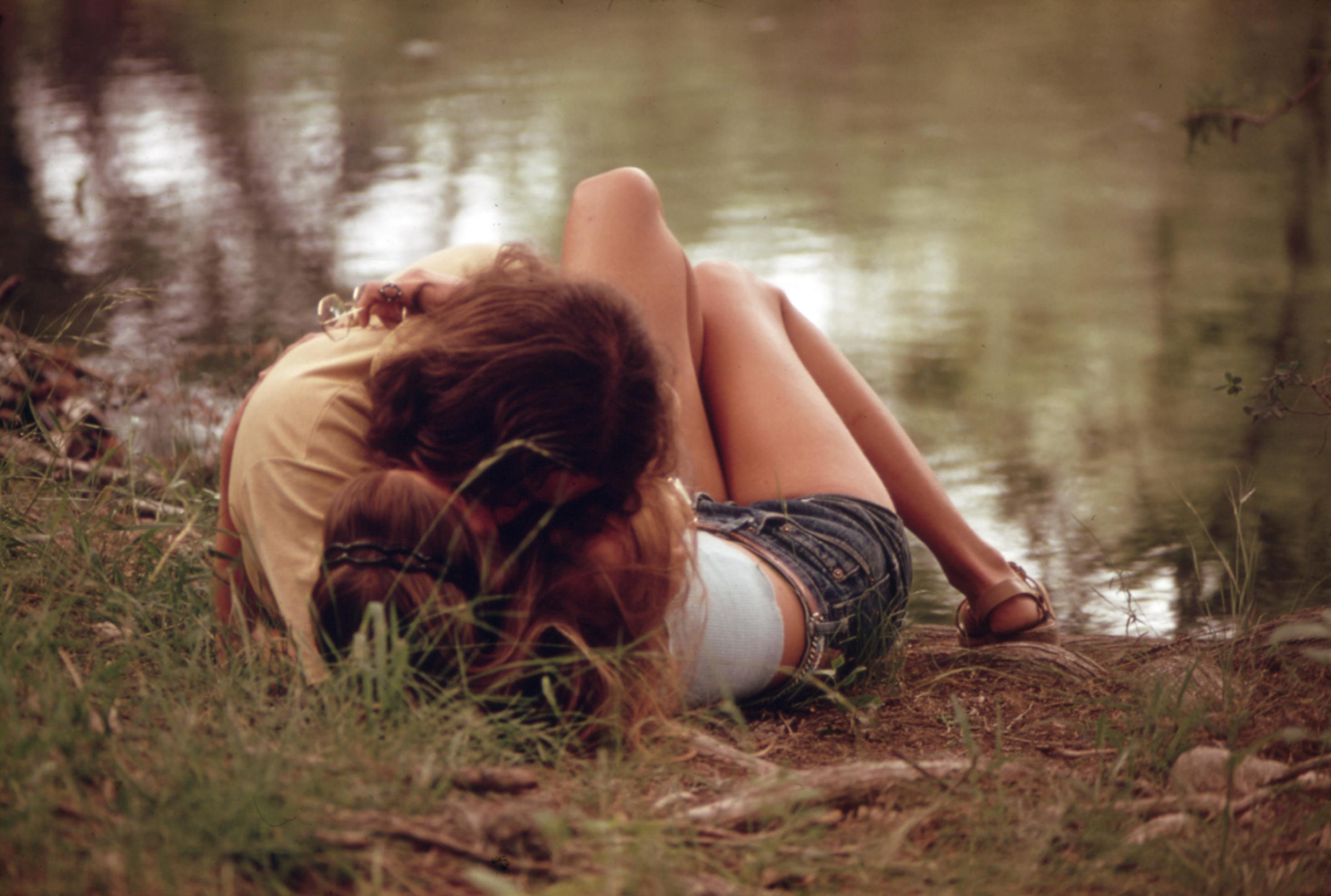 An einem sommerlichen Seeufer zwischen Gras liegt ein Paar junger Menschen, sich innig küssend. Er hat sich über sie gebeugt, man sieht fast nur seine dichten braunen Haare. Sie liegt, mit hellem Top und kurzer Hose bekleidet, auf dem Rücken und umarmt ihn.