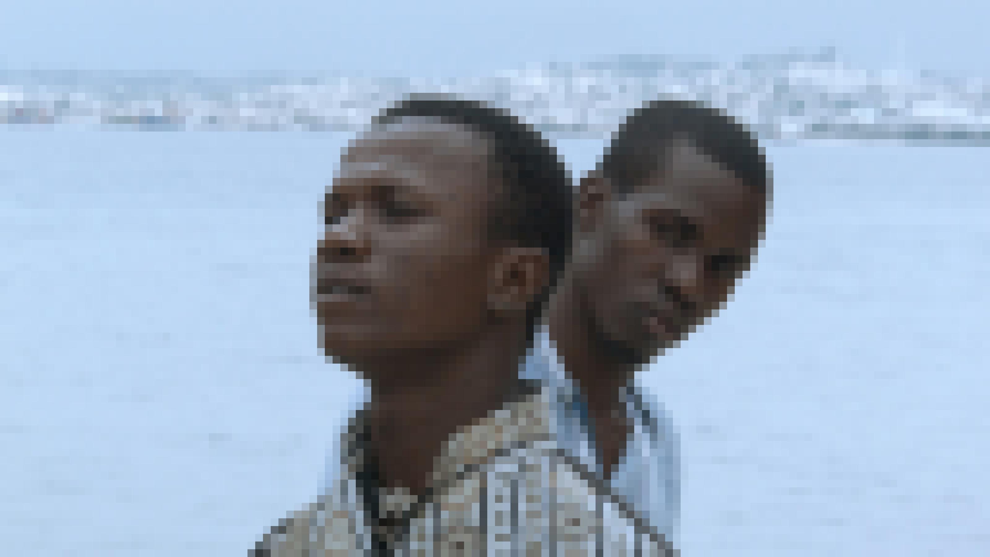 Zwei junge Männer aus Haiti vor der südlicher Küstenlandschaft, die sich gegenseitig belauern.