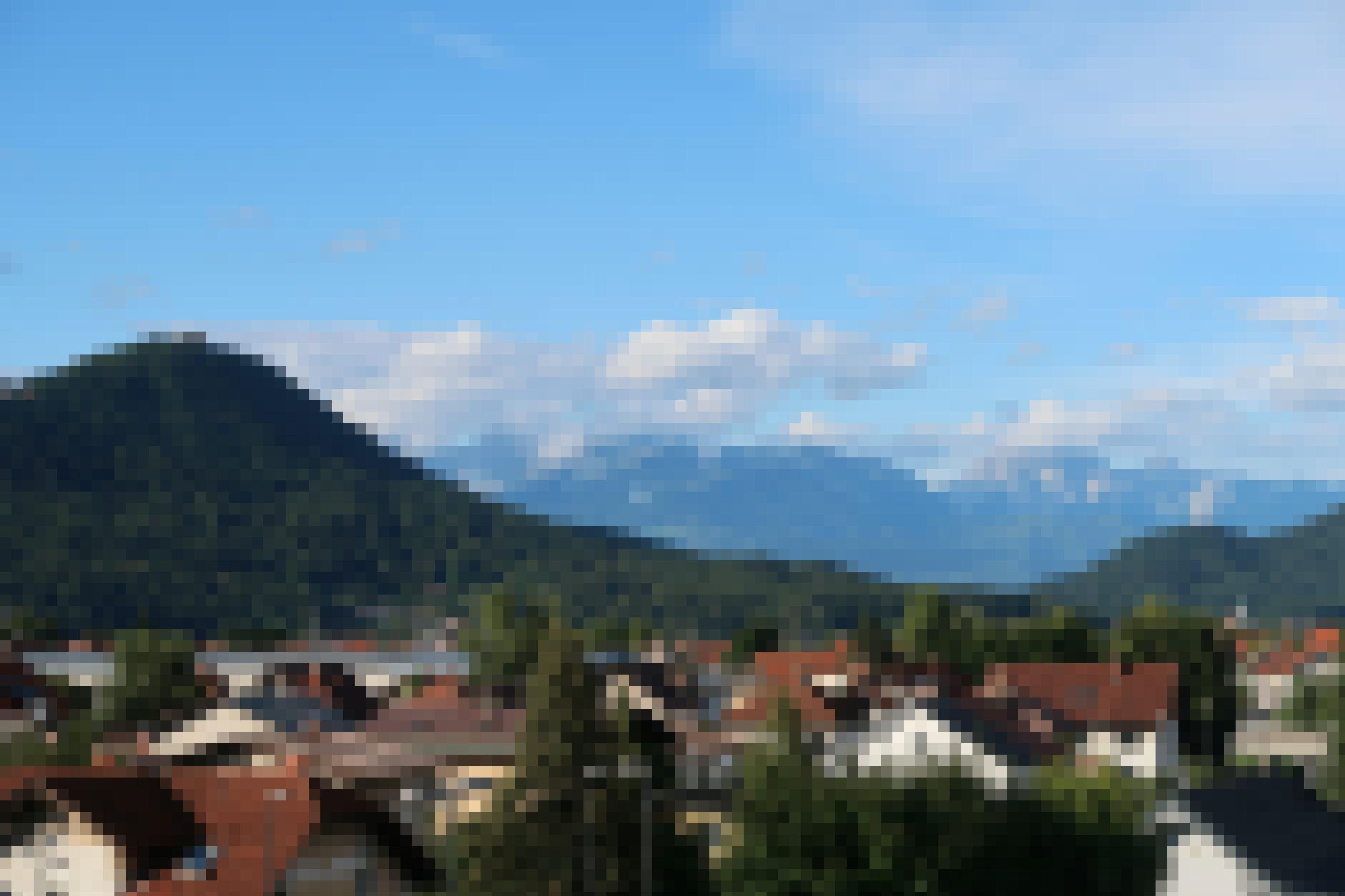Blick auf die Alpen mit Häusern im Vordergrund.