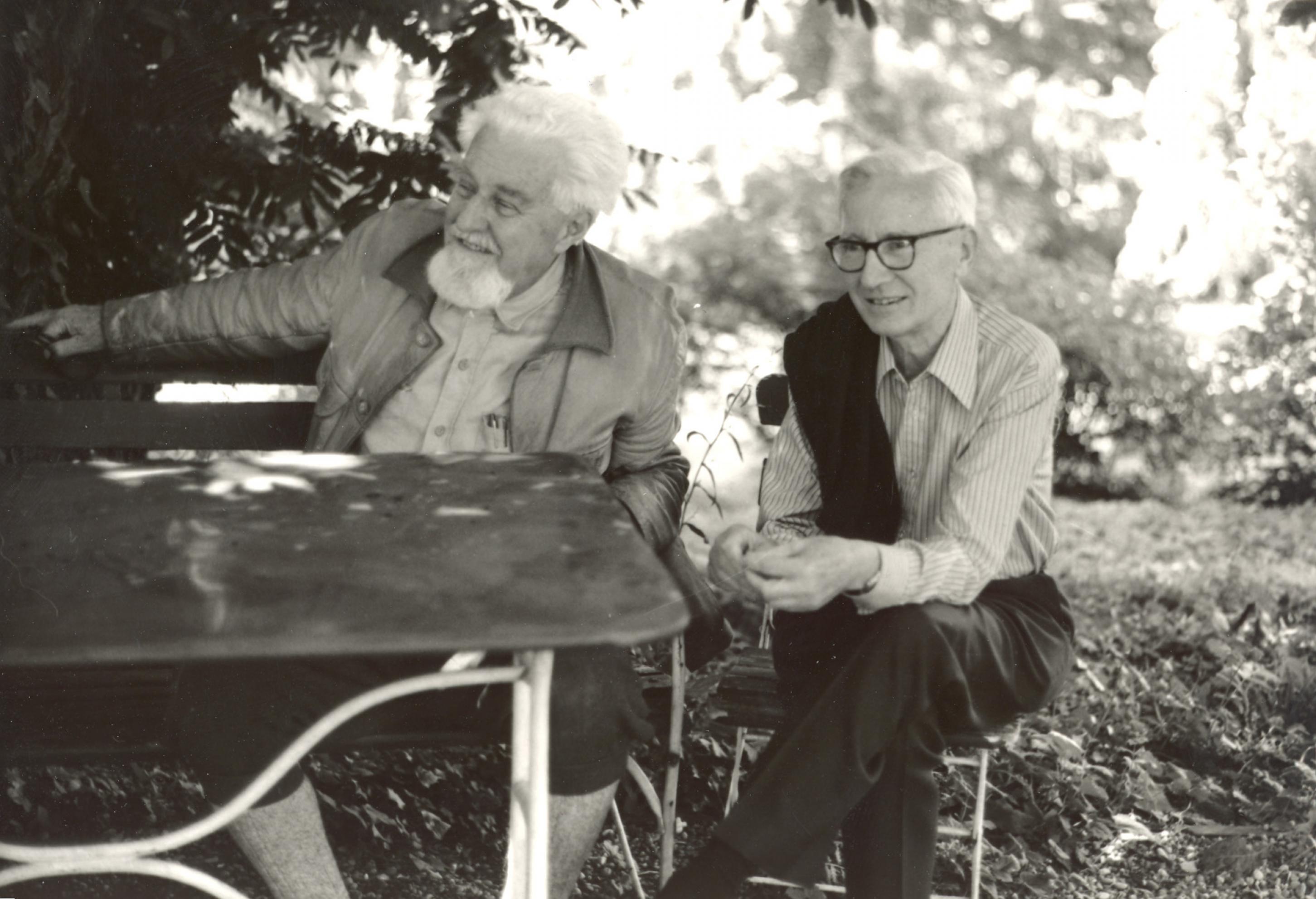 Das Bild zeigt die beiden Wissenschaftler Nikolaas Tinbergen und Konrad Lorenz in einem Garten an einem Tisch sitzend.