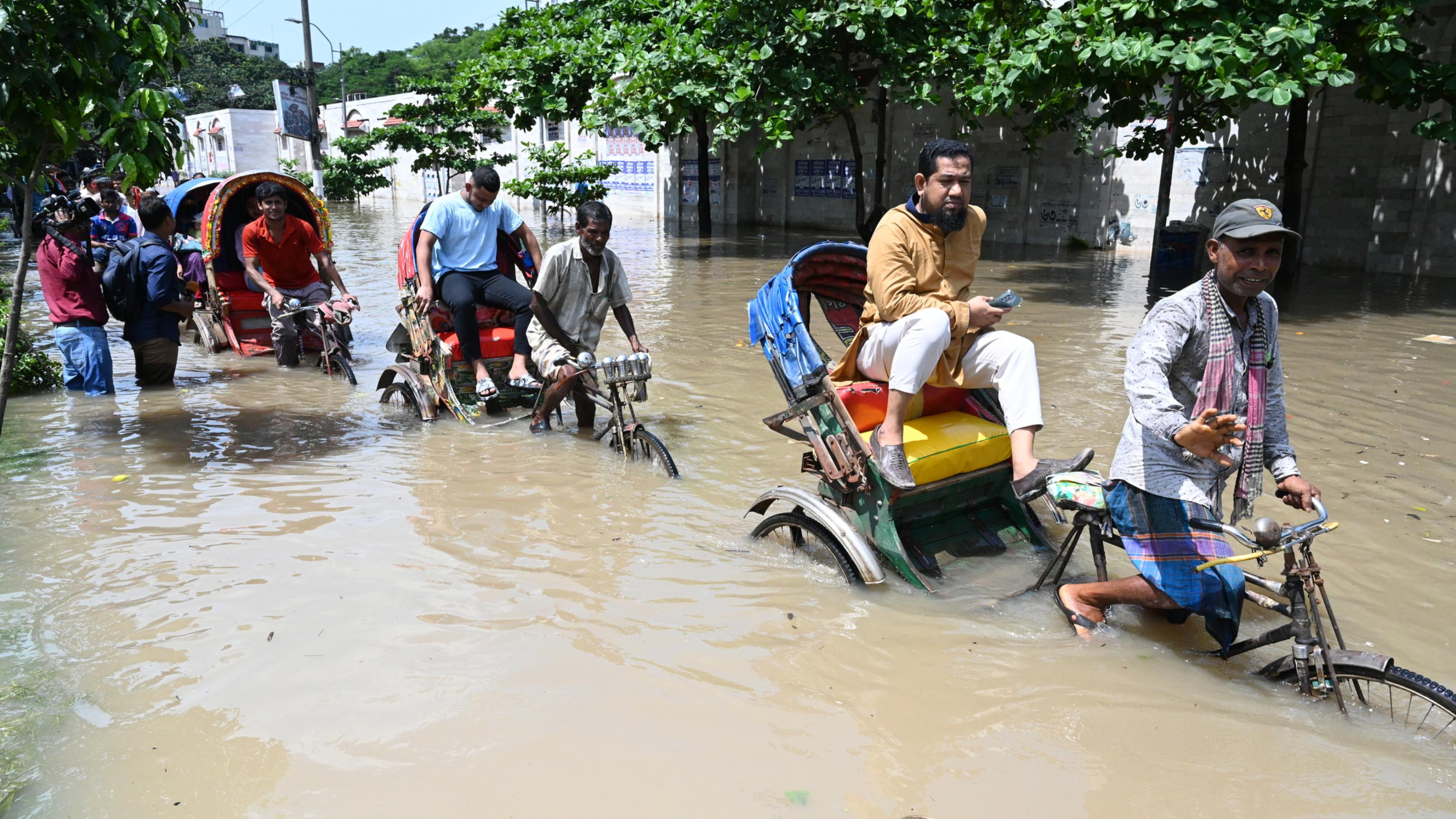 Fahrzeuge versuchen zu fahren und Bürger laufen am 22. September 2023 durch die überschwemmten Straßen von Dhaka in Bangladesch.