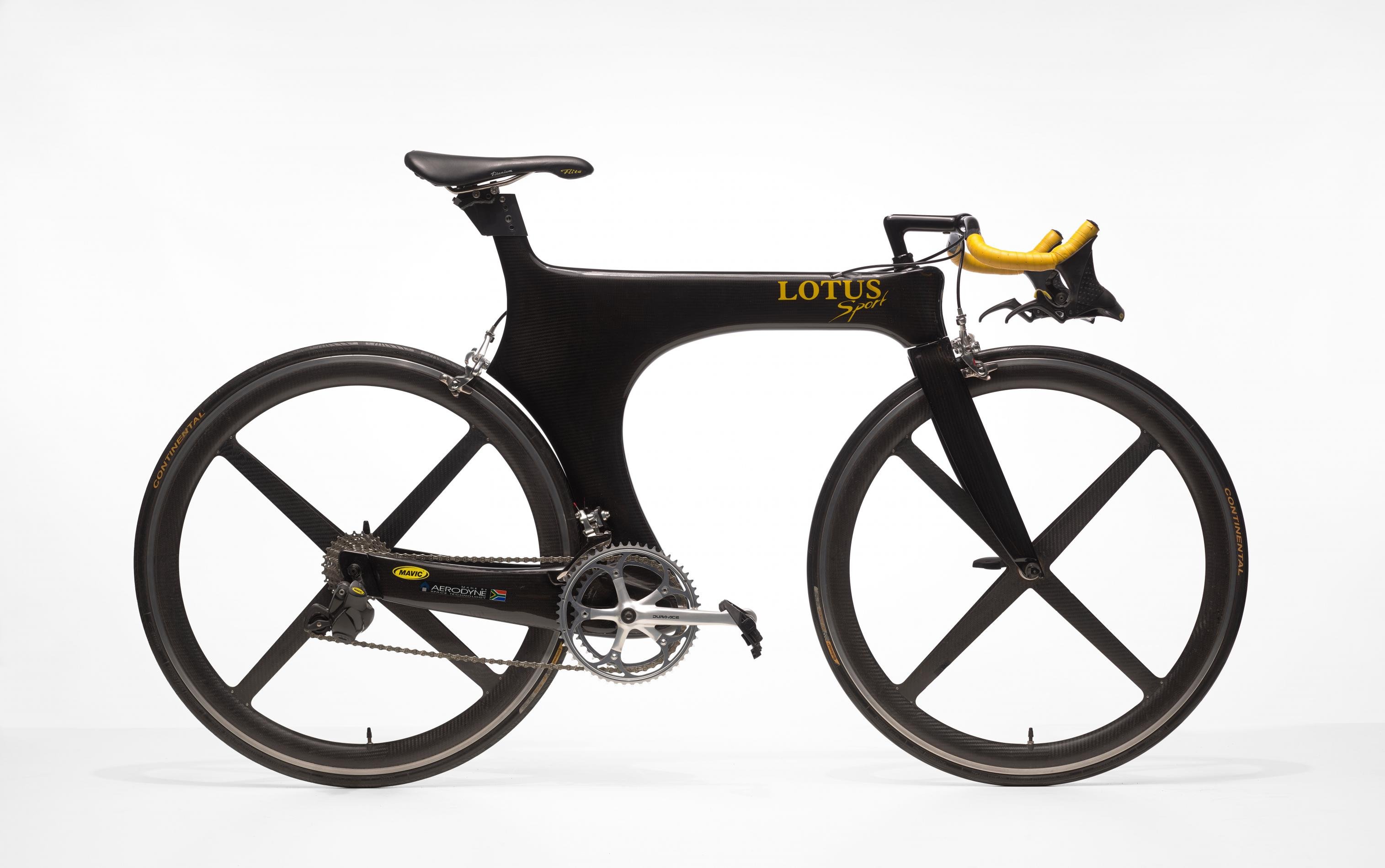 Schwarzes Rennrad mit überdickem Rahmen und gelbem Lenkerband und Aufdruck „Lotus Sport“.