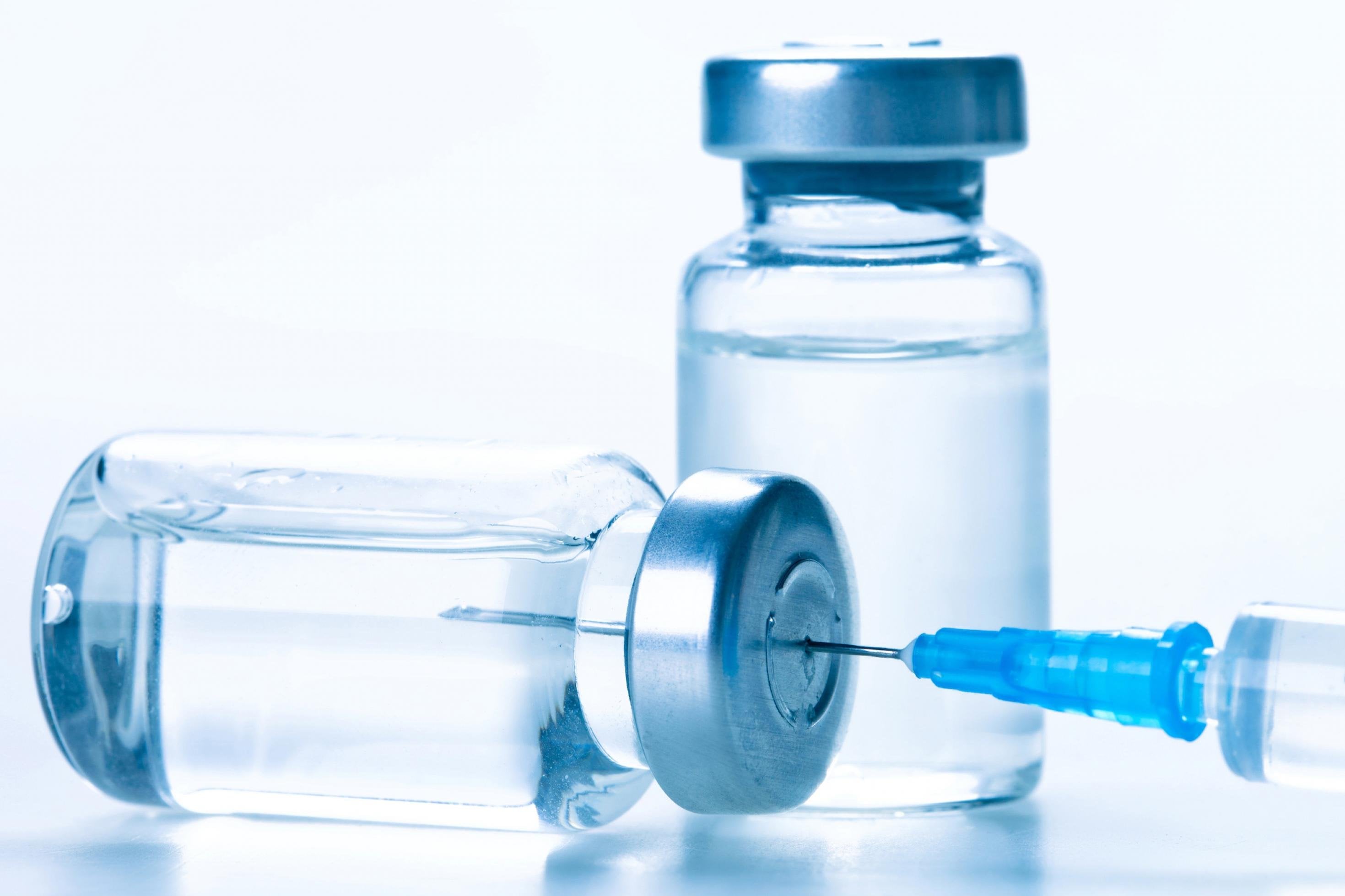 Medizinische Durchstechflaschen aus Glas mit einer Impfspritze.