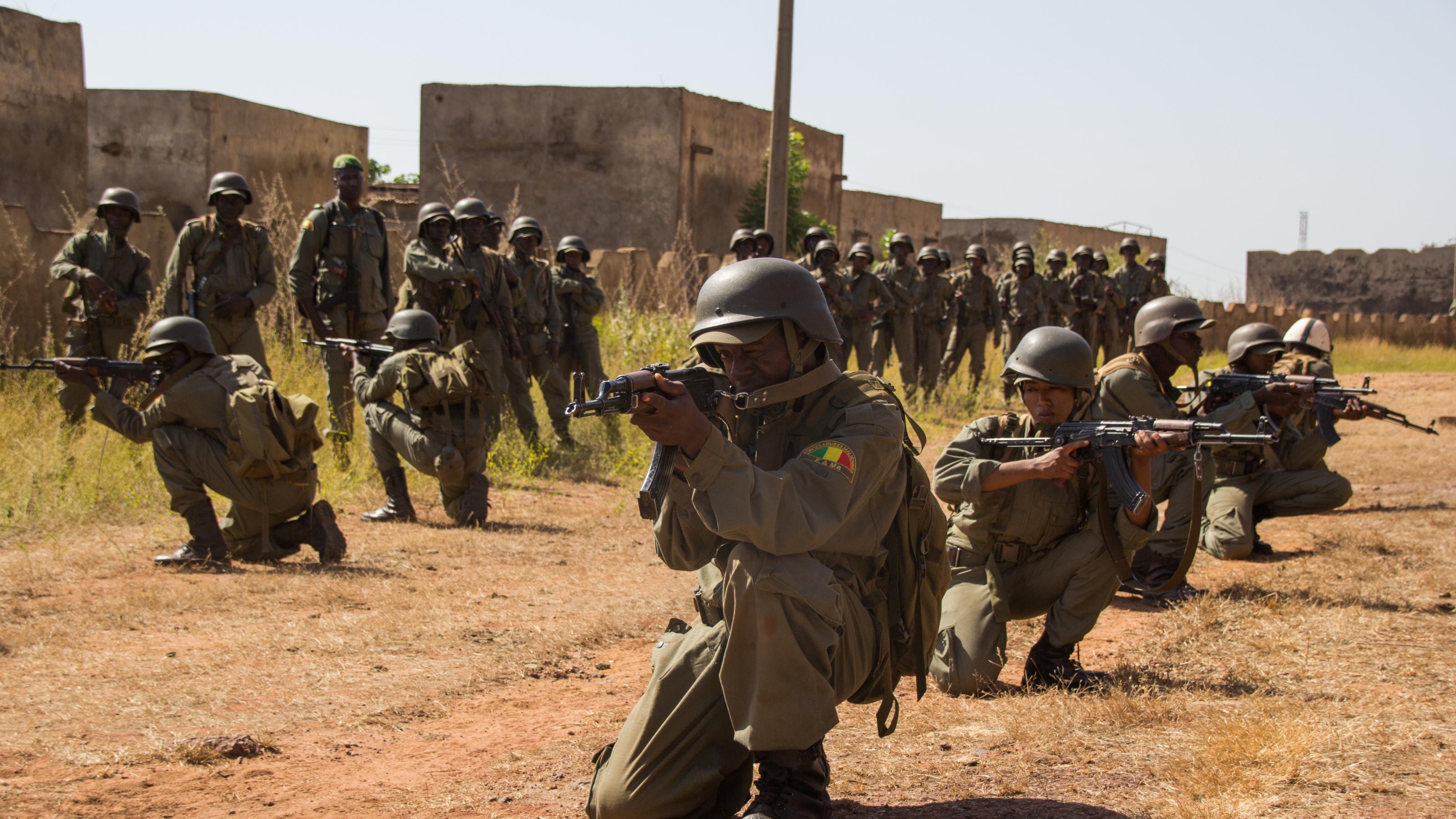 Malische Soldaten knien hintereinander in einer Reihe, die Gewehre im Anschlag. Sie üben den Häuserkampf.