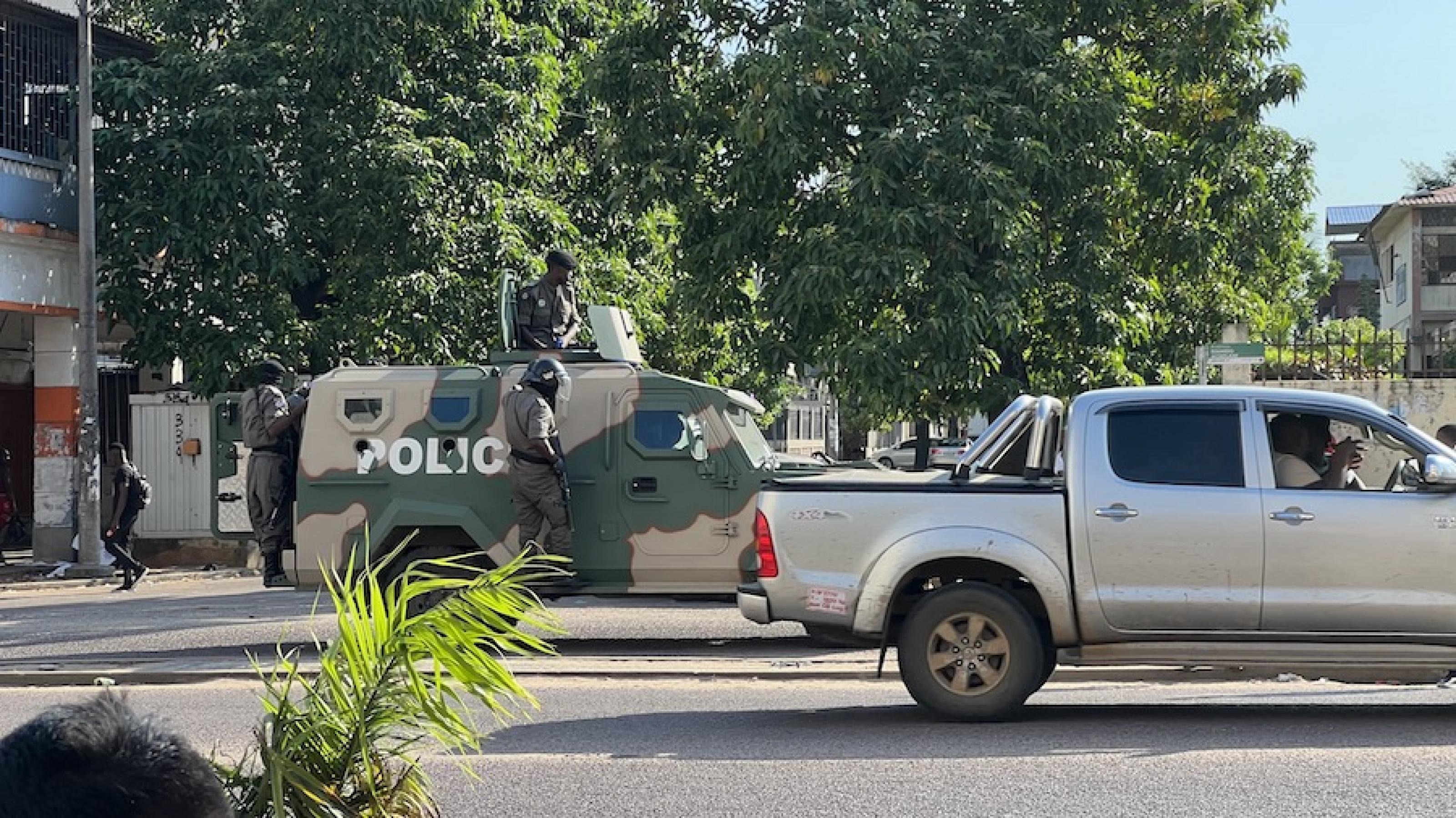 Hinter einem Pickup steht ein gepanzertes Polizei-Einsatzfahrzeug auf der Straße