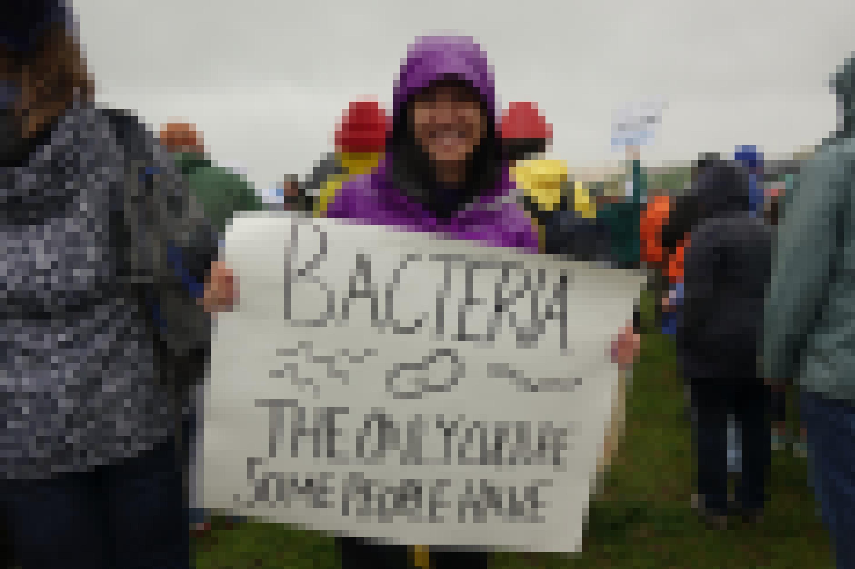 Eine Frau hält ein Schild hoch. Darauf: Bacteria – the only culture some people have.