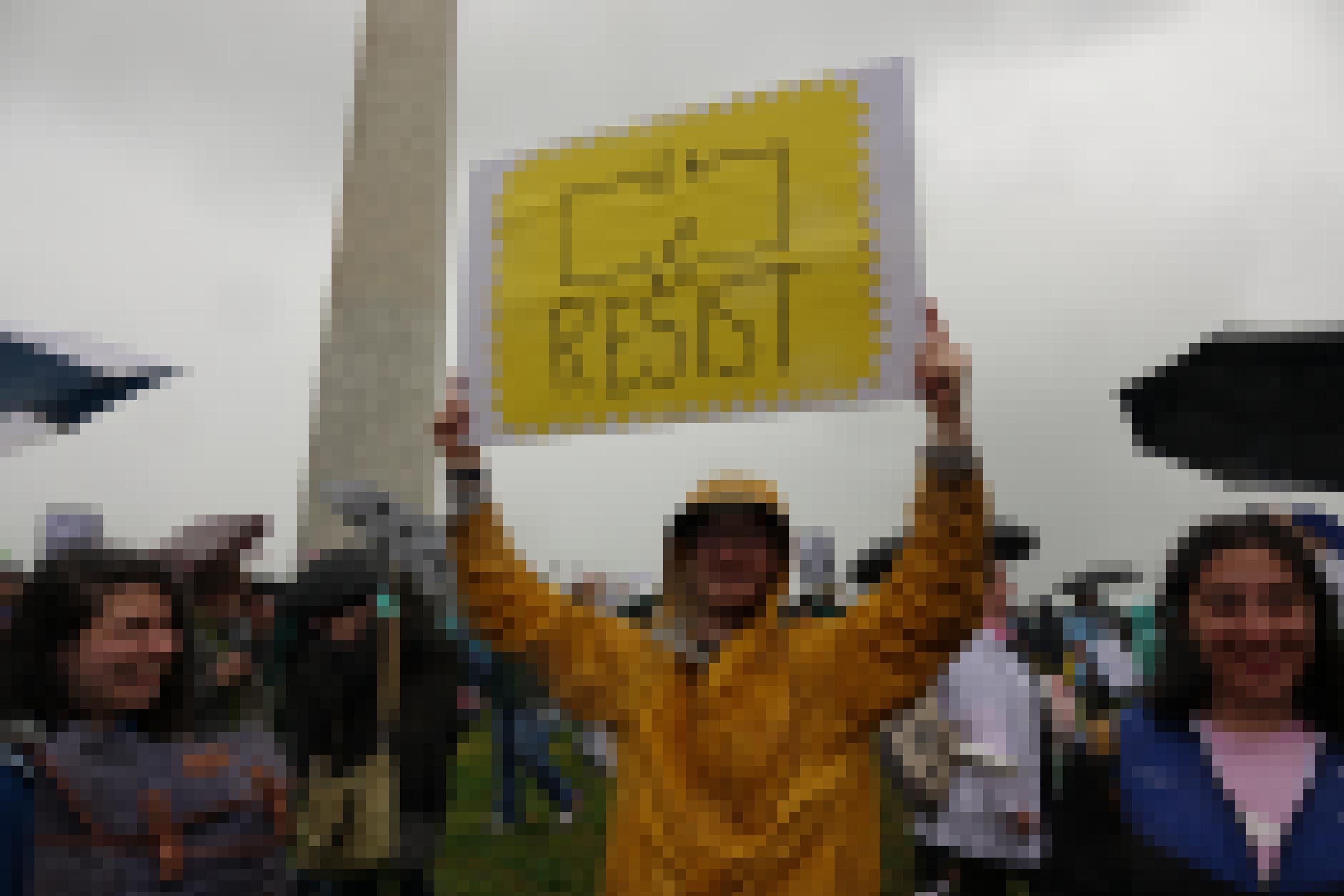 Ein Mann hält ein Schild hoch, darauf ist ein Schaltkreis zu sehen und das Wort: Resist