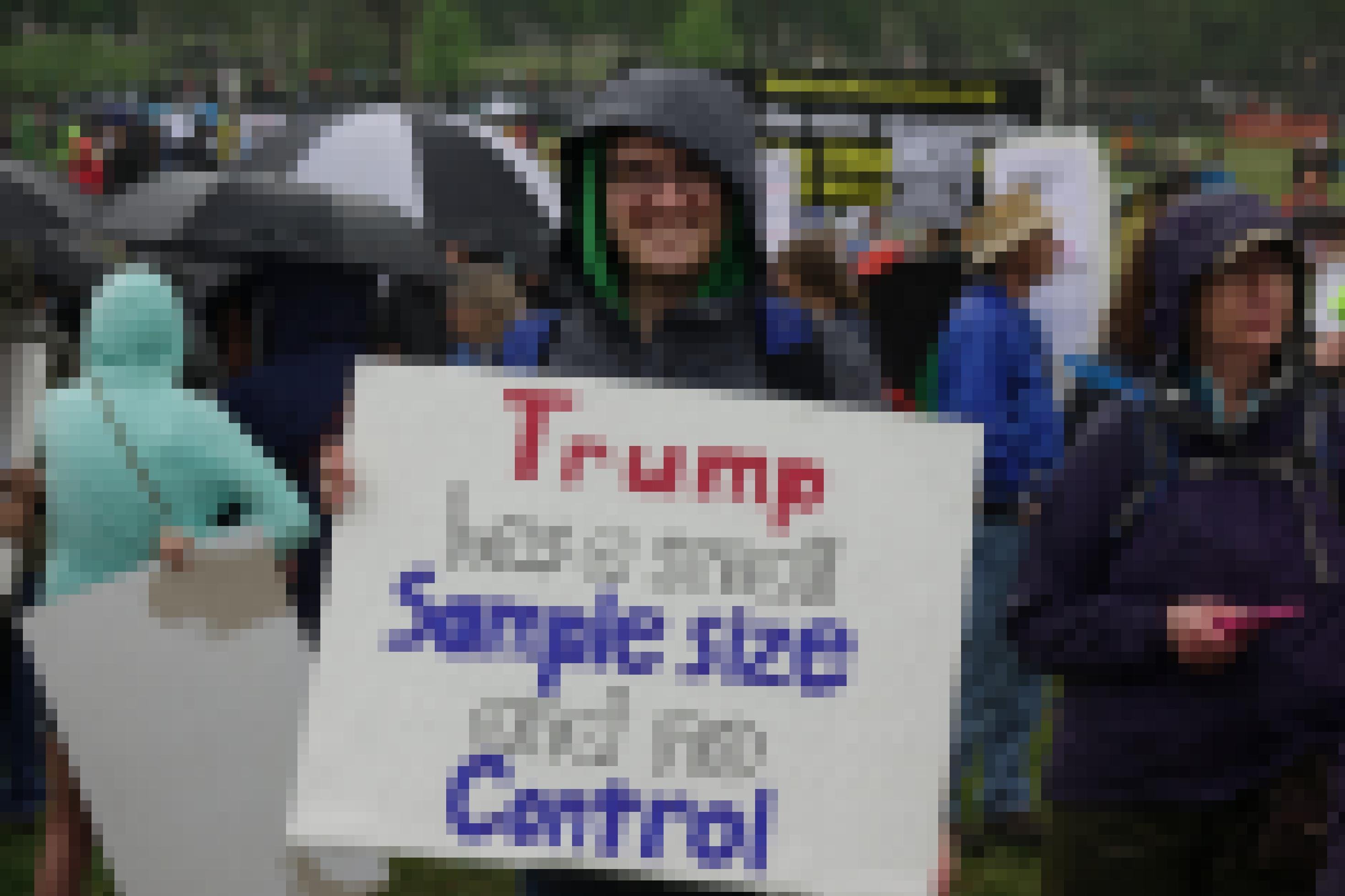 Ein junger Mann hält ein Schild hoch: Trump has a small sample size and no control