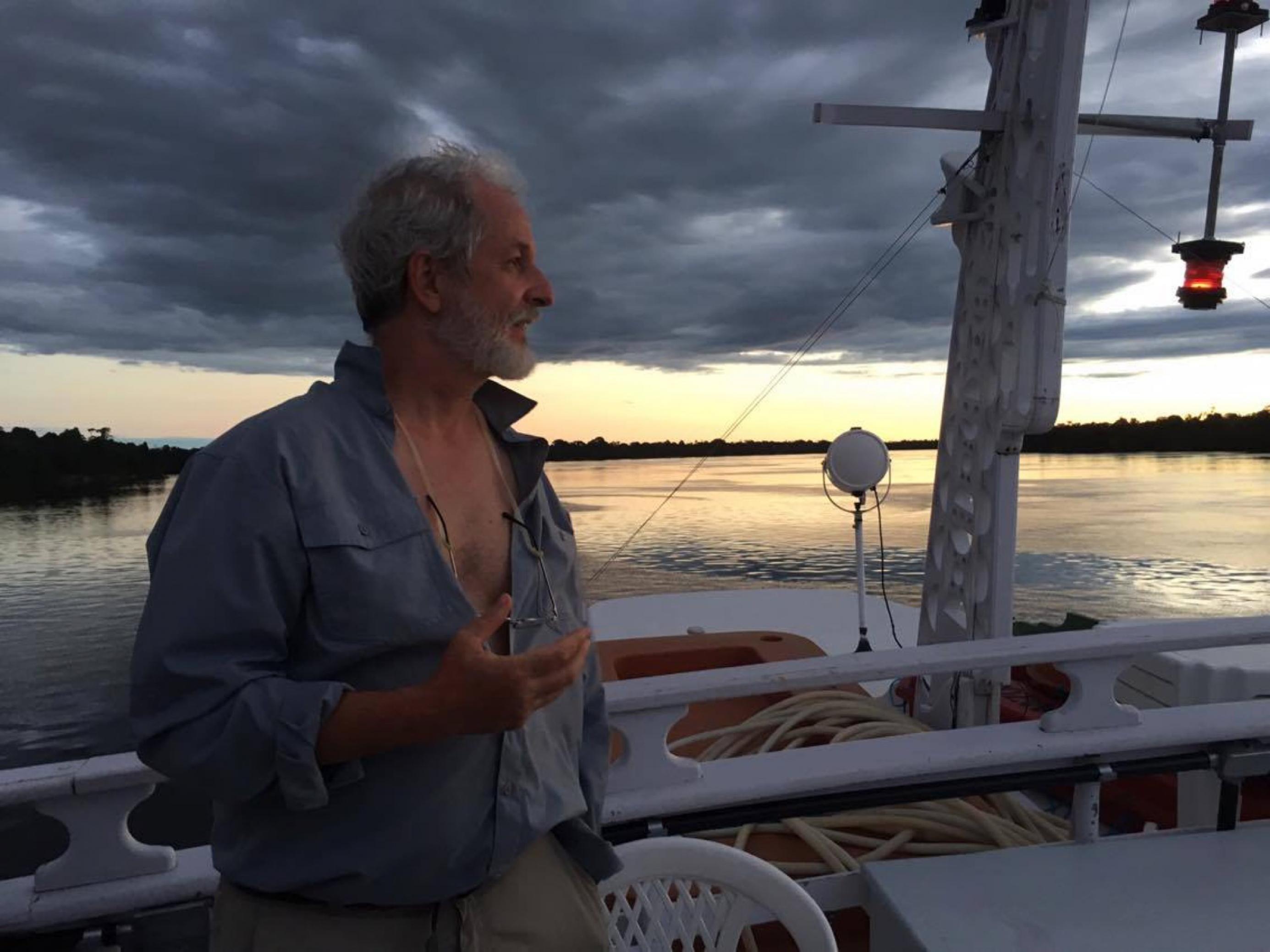 Der Ornithologe Mario Cohn-Haft steht bei Sonnenuntergang an Deck eines Bootes