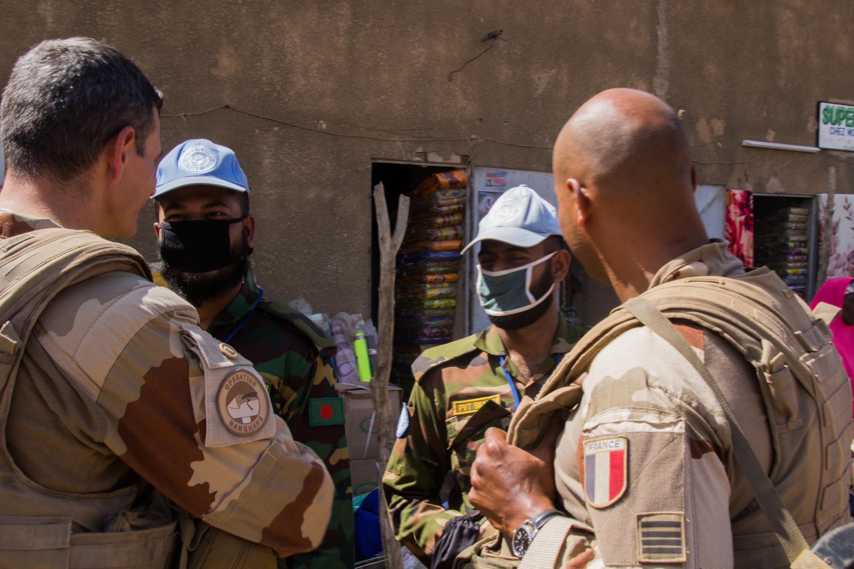 Halb im Anschnitt von hinten sind zwei französische Soldaten zu sehen, von vorne zwei ihrer maleschen Kollegen, mit Gesichtsmasken.