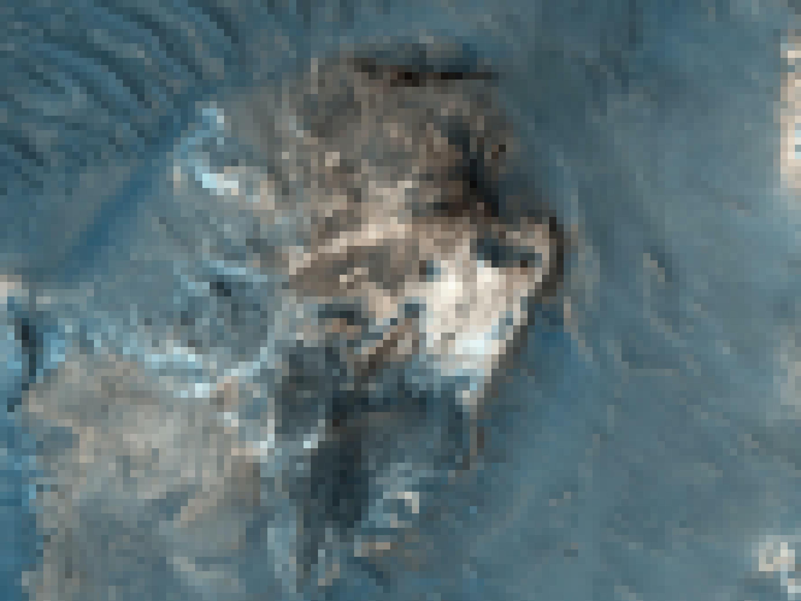 Satellitenbild eines zerrütteten Höhenzugs aus weißlich-grauem Gestein, das von einer dunkleren Ebene umgeben ist.