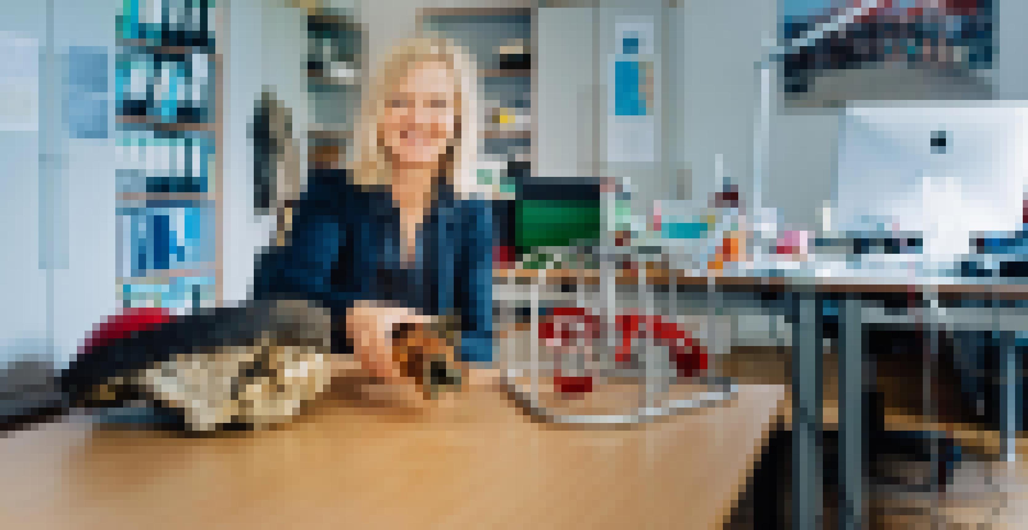 Eine Frau mit mittellangen blonden Haaren sitzt an einem Tisch in einem Büro und zeigte Modelle und Fundstücke aus der Meeresforschung.