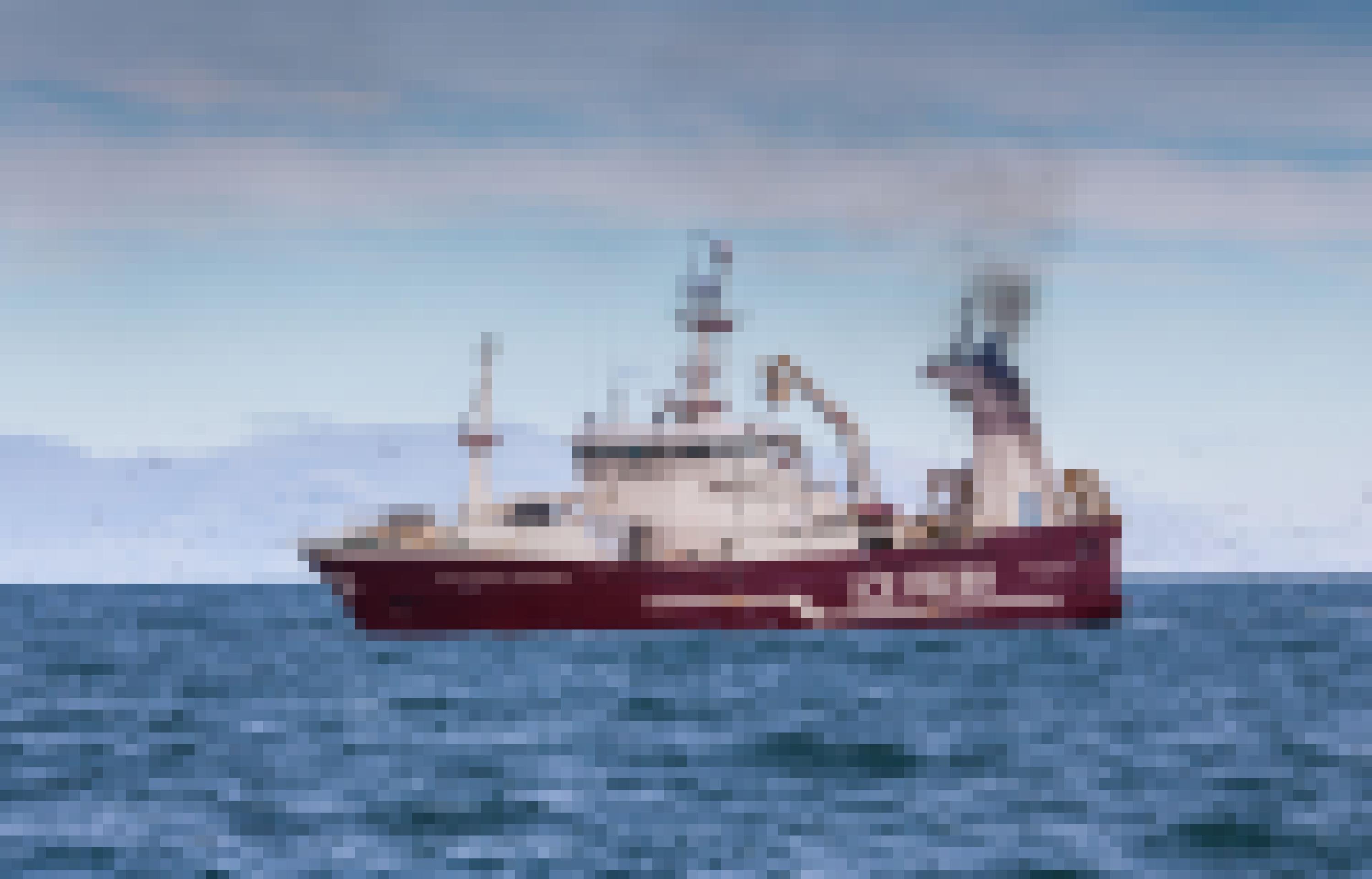 Rot und weiß gestrichenes Fischereiboot mit der isländischen Küste im Hintergrund.