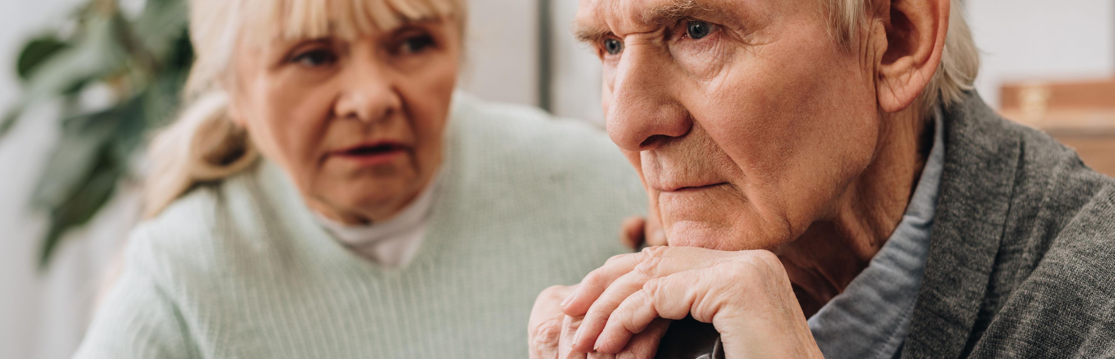 Eine Frau spricht zu einem alten Mann, der einen Gehstock umfasst hält und ernst geradeaus blickt. Vier von fünf pflegebedürftige Menschen werden zu Hause versorgt – oft von Angehörigen.