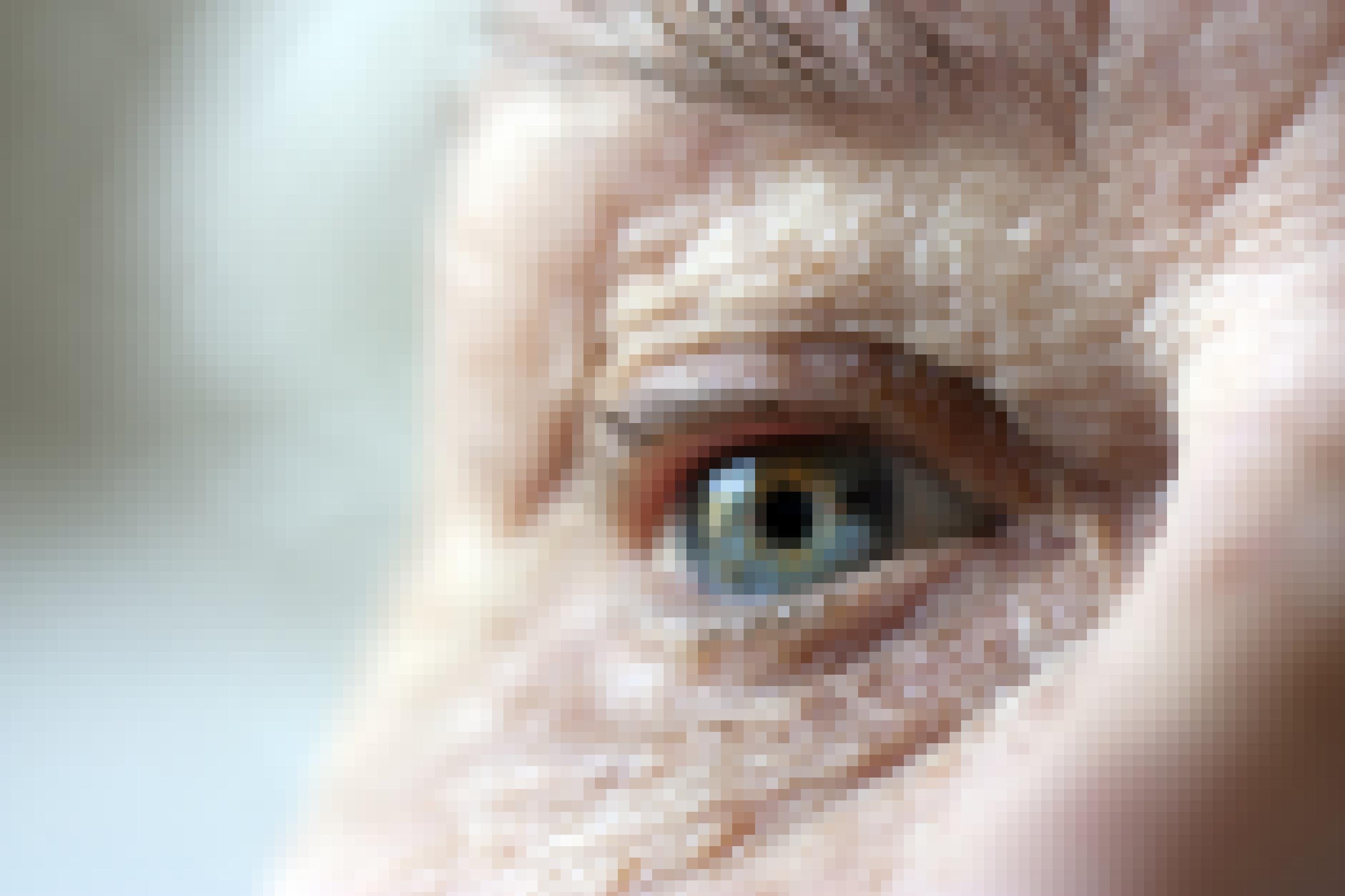 Das Foto zeigt die Nahaufnahme des Augenbereichs eines älteren Menschen. Deutlich sind um das Auge herum Falten zu erkennen. Auch ein Teil der Augenbraue mit einigen grauen Haaren darin, ist scharf zu sehen. Die Nase und die hintere Wangenpartie verschwimmen in der Unschärfe.