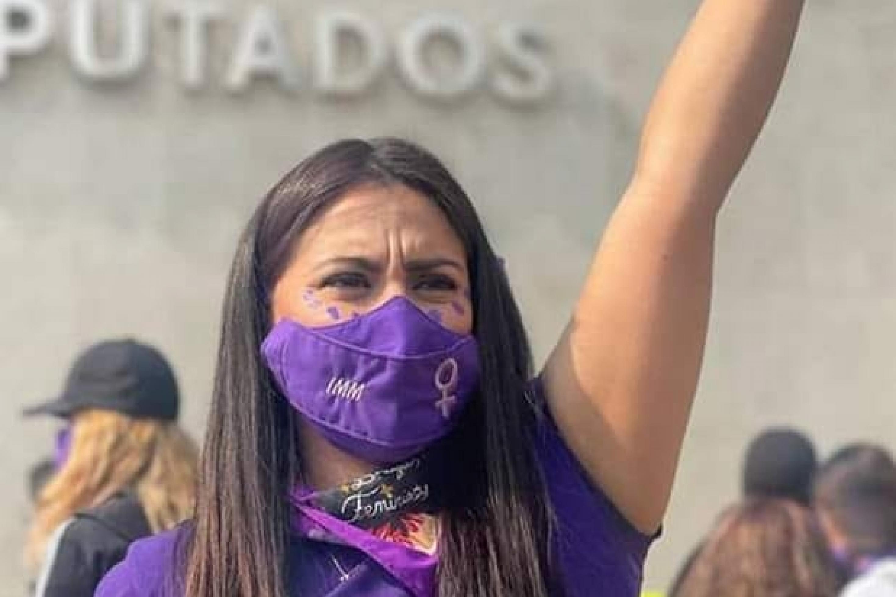 Olimpia Coral vermummt und mit hochgereckter Faust im lila Shirt bei einer Frauendemonstration in Mexiko.