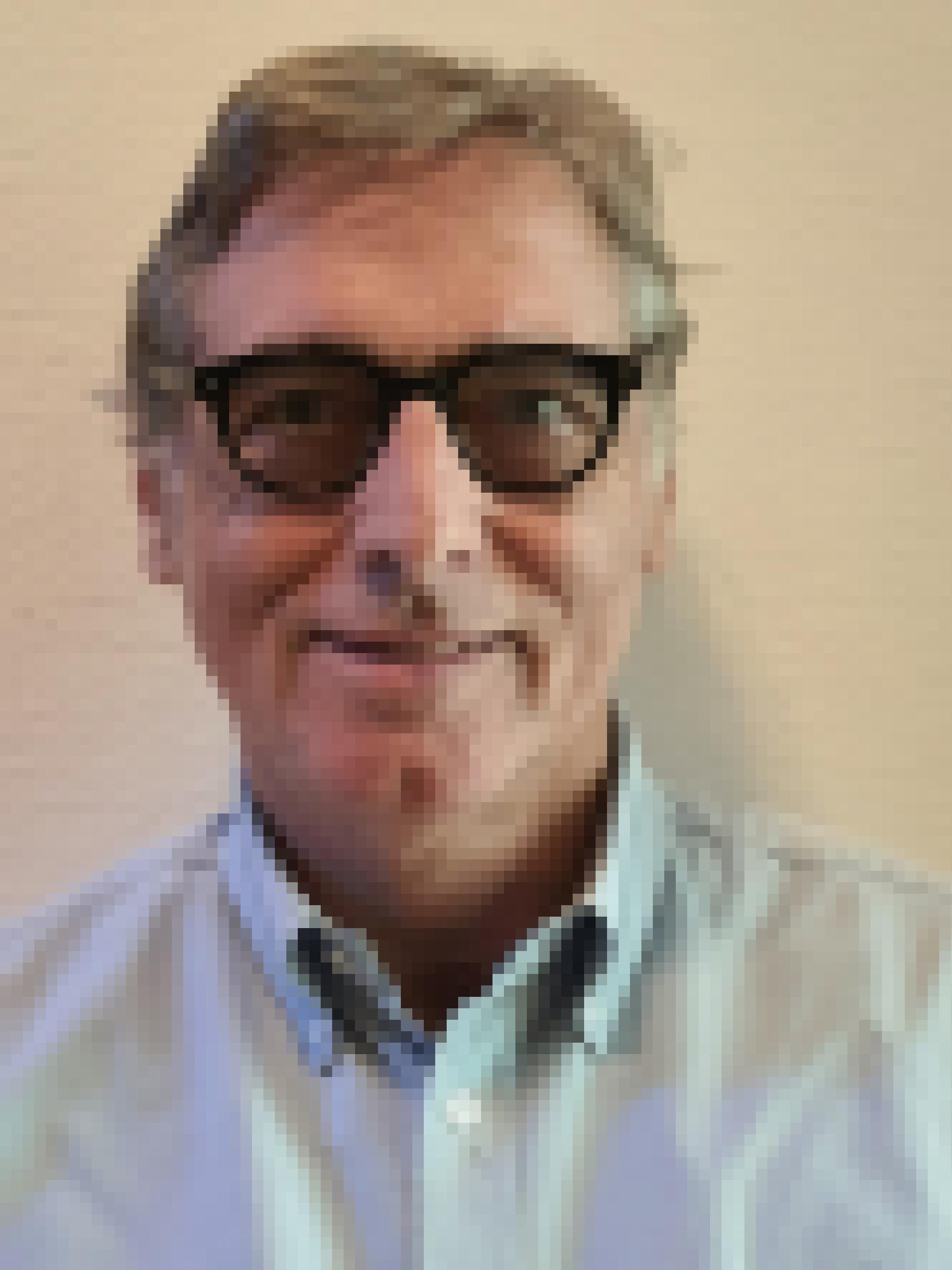 Mann mit grauem schütterem Haar, schwarze Brille mit leicht getönten Gläsern