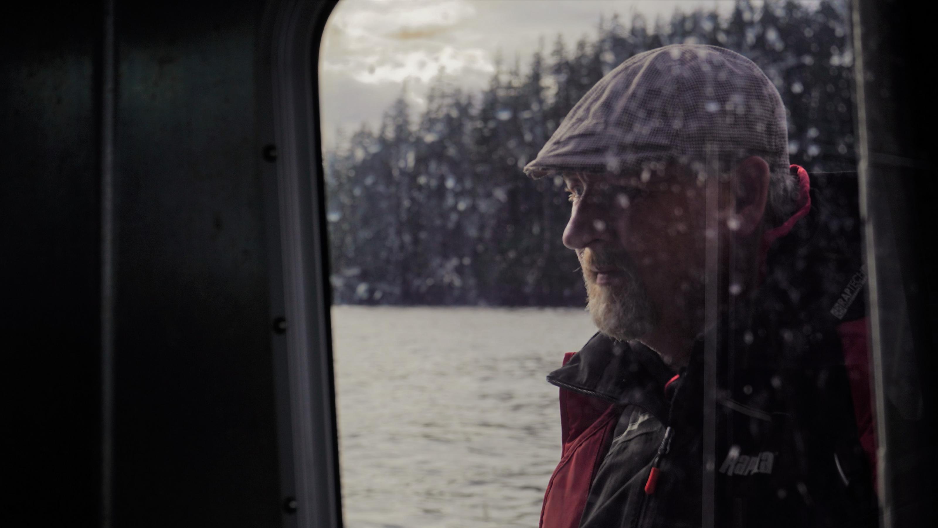 Die dunkle Silhouette eines älteren Mannes ist durch ein Bootsfenster zu sehen.