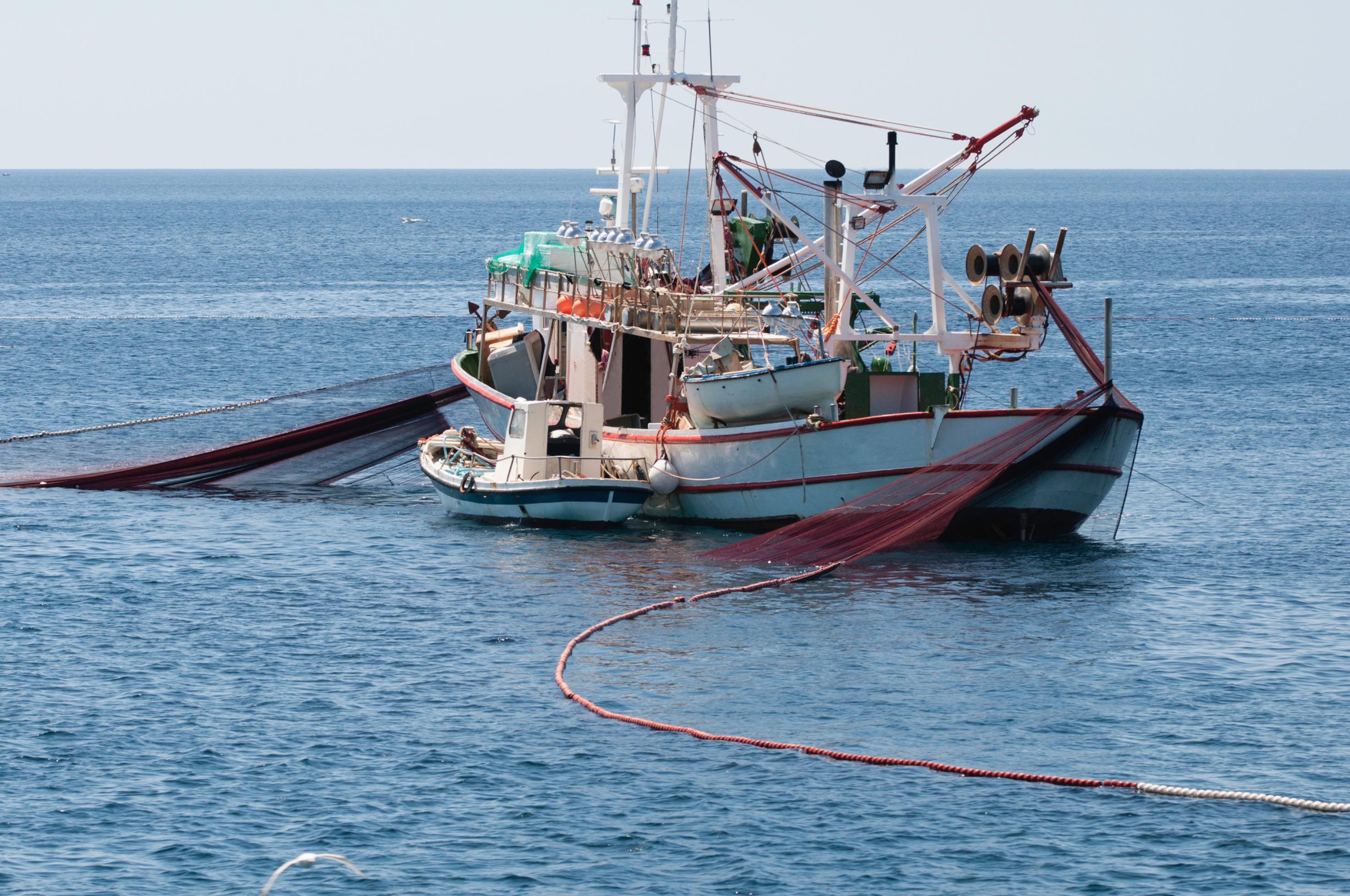 Mittelgroßes Fischereiboot mit ausliegendem Netz.