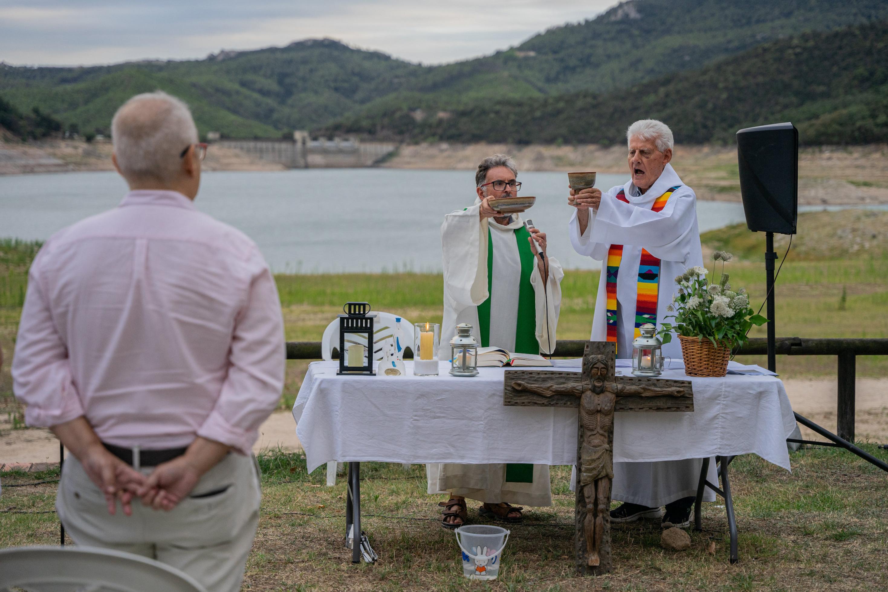 Priester bei Gottesdienst im Freien vor einem ziemlich leeren Staubecken.