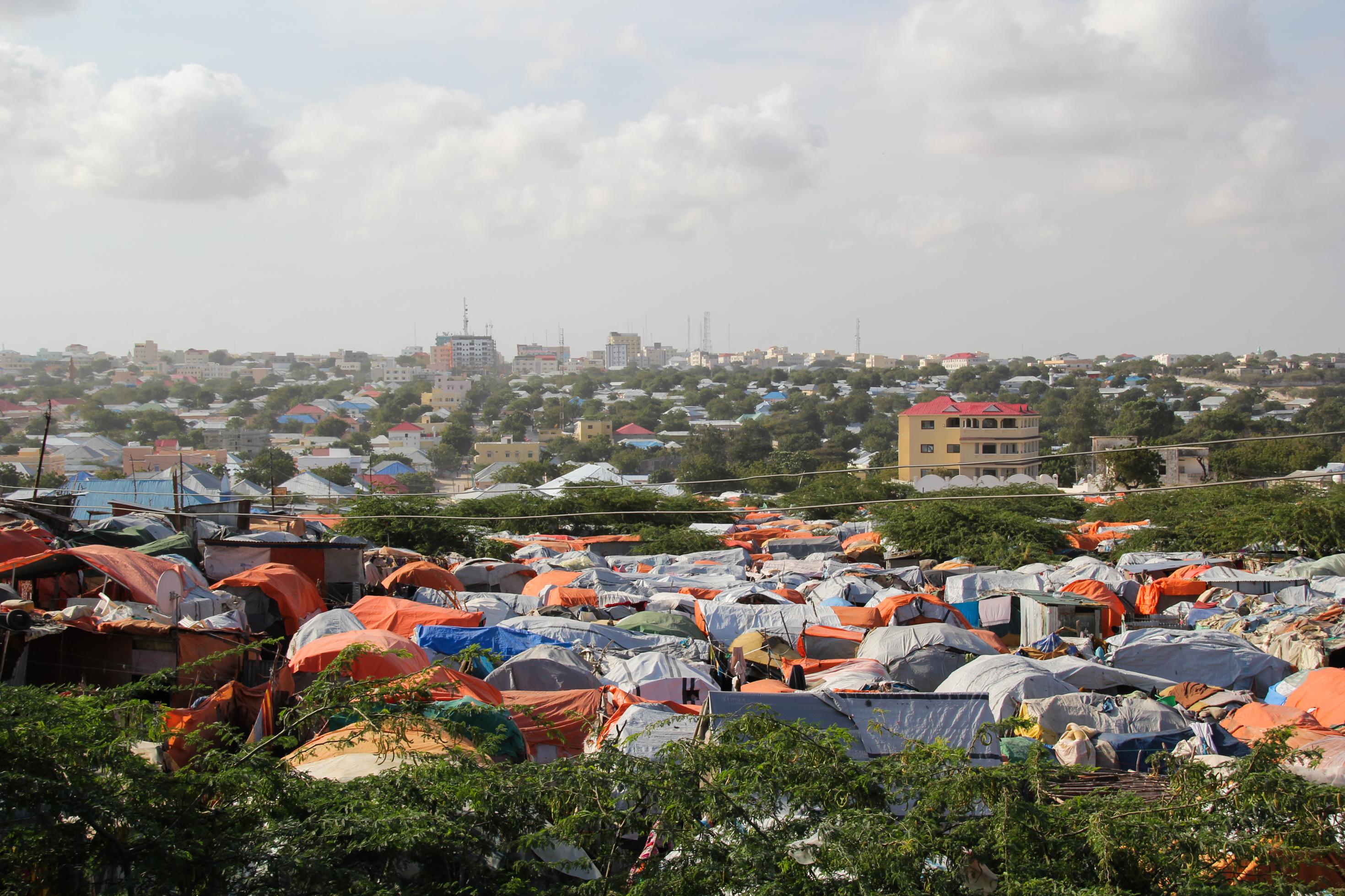 Blick auf Mogadischu, die Hauptstadt Somalias. Im Vordergrund Zelte, weiter hinten Hausdächer und Gebäude.