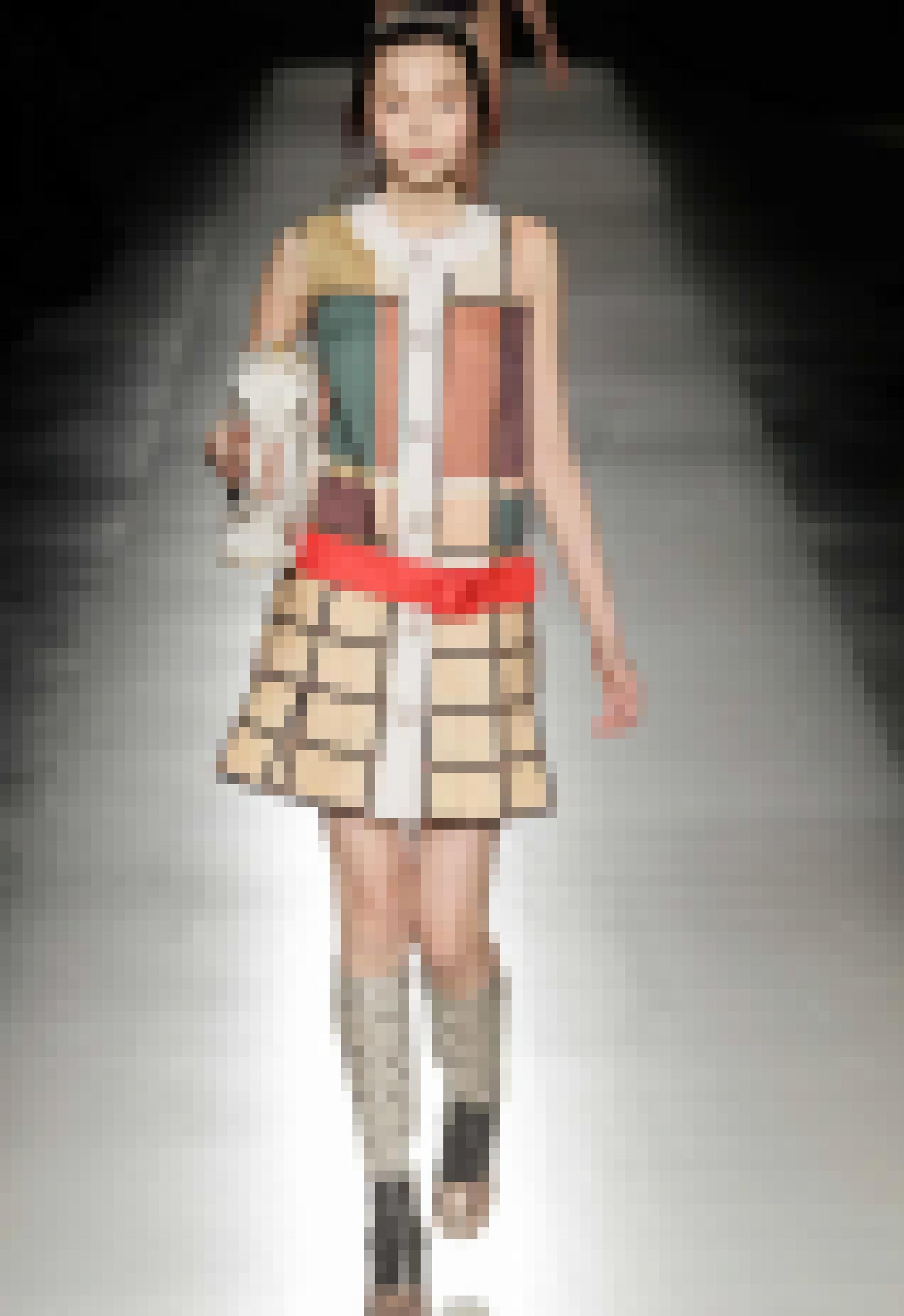 Eine schmale junge Frau, die ein Kleid mit pliessiertem Rock trägt, das aus einem Stoff mit einem aubwechselungsreichen Karomuster gefertigt ist.   Karomuster