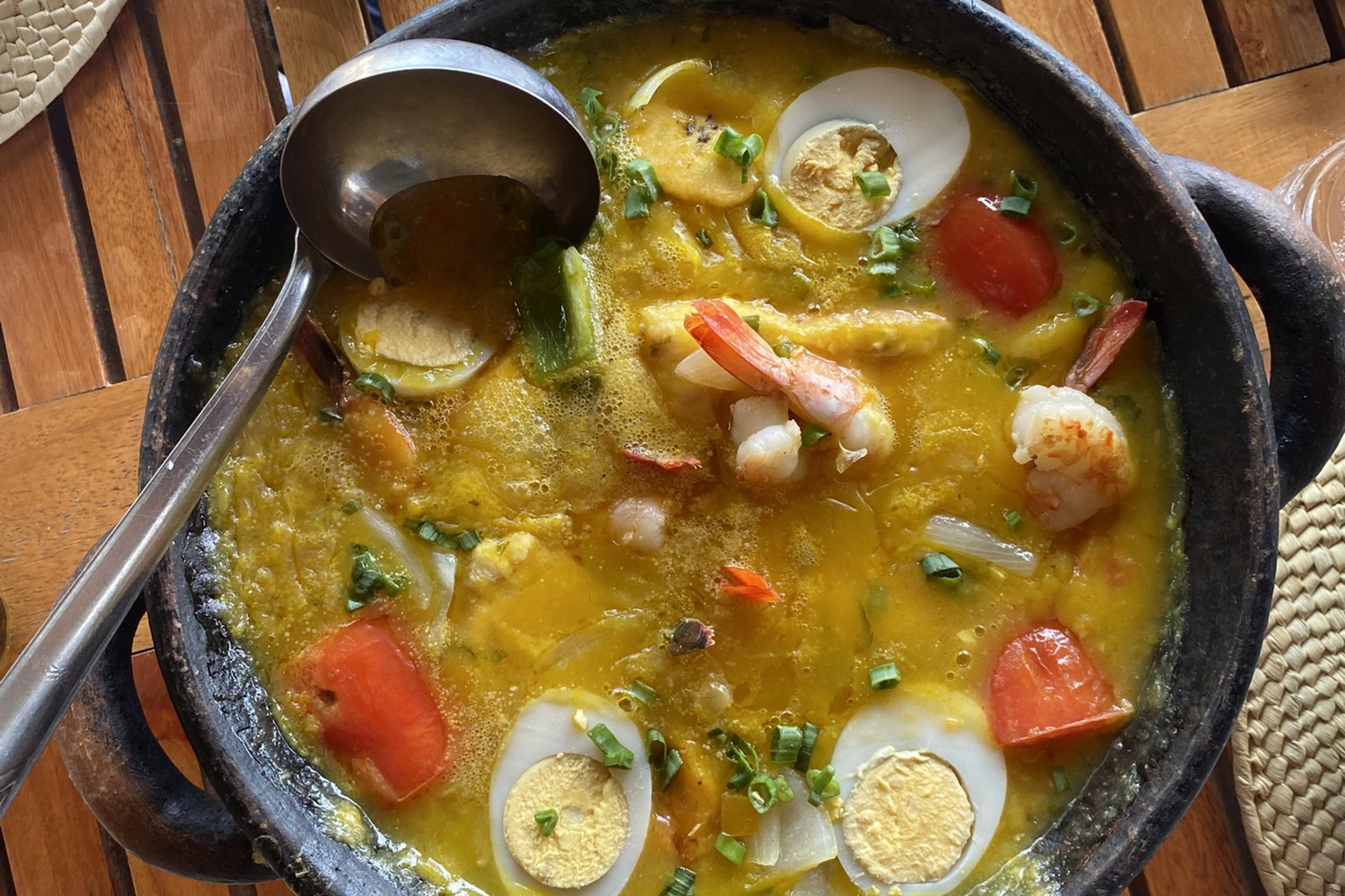 Ein schwarzer Tontopf mit Garnelen, Fisch und Ei