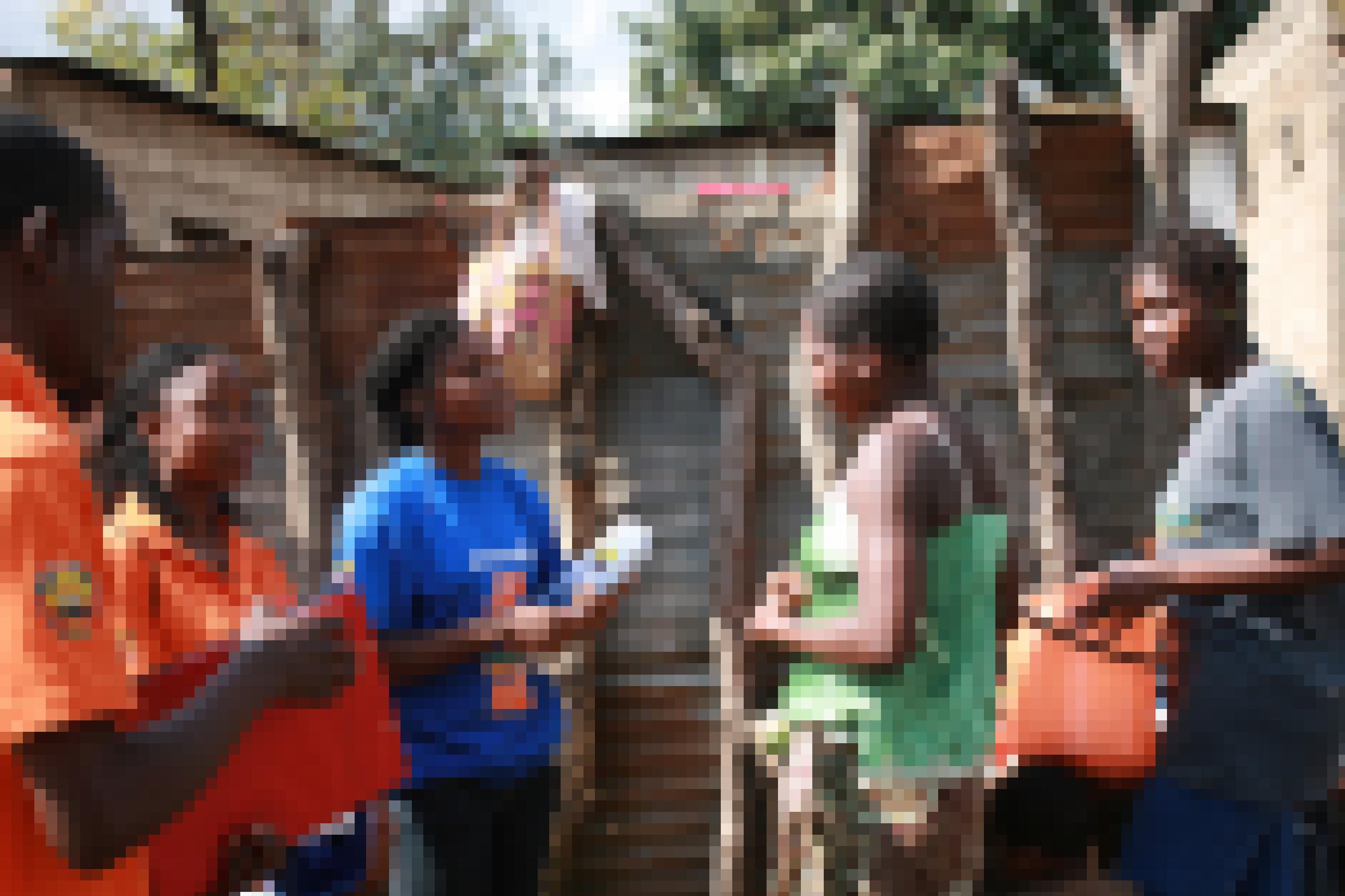 Drei Aktivistinnen sprechen mit einer jungen Frau, ein Mann hört zu, dahinter eine der typischen Wellblechverkleidungen eines der Häuser in dem Armenviertel von Maputo