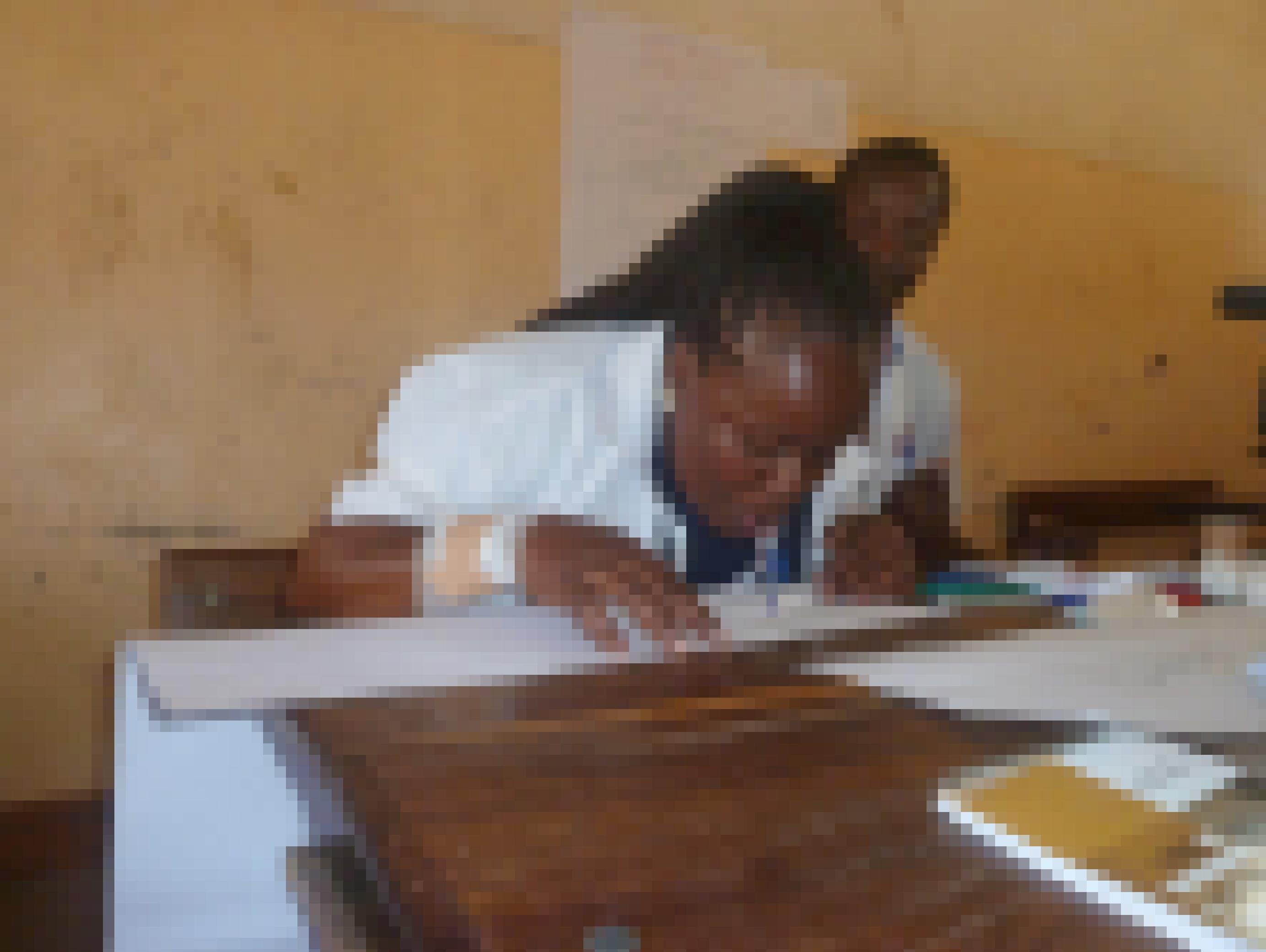 Die Lehrerin hat ihre Arme hochgebunden und einen Stift im Mund. Sie soll schreiben, ohne ihre Hände zu benutzen, um sich in die Lage von Schülern mit Behinderungen zu versetzen