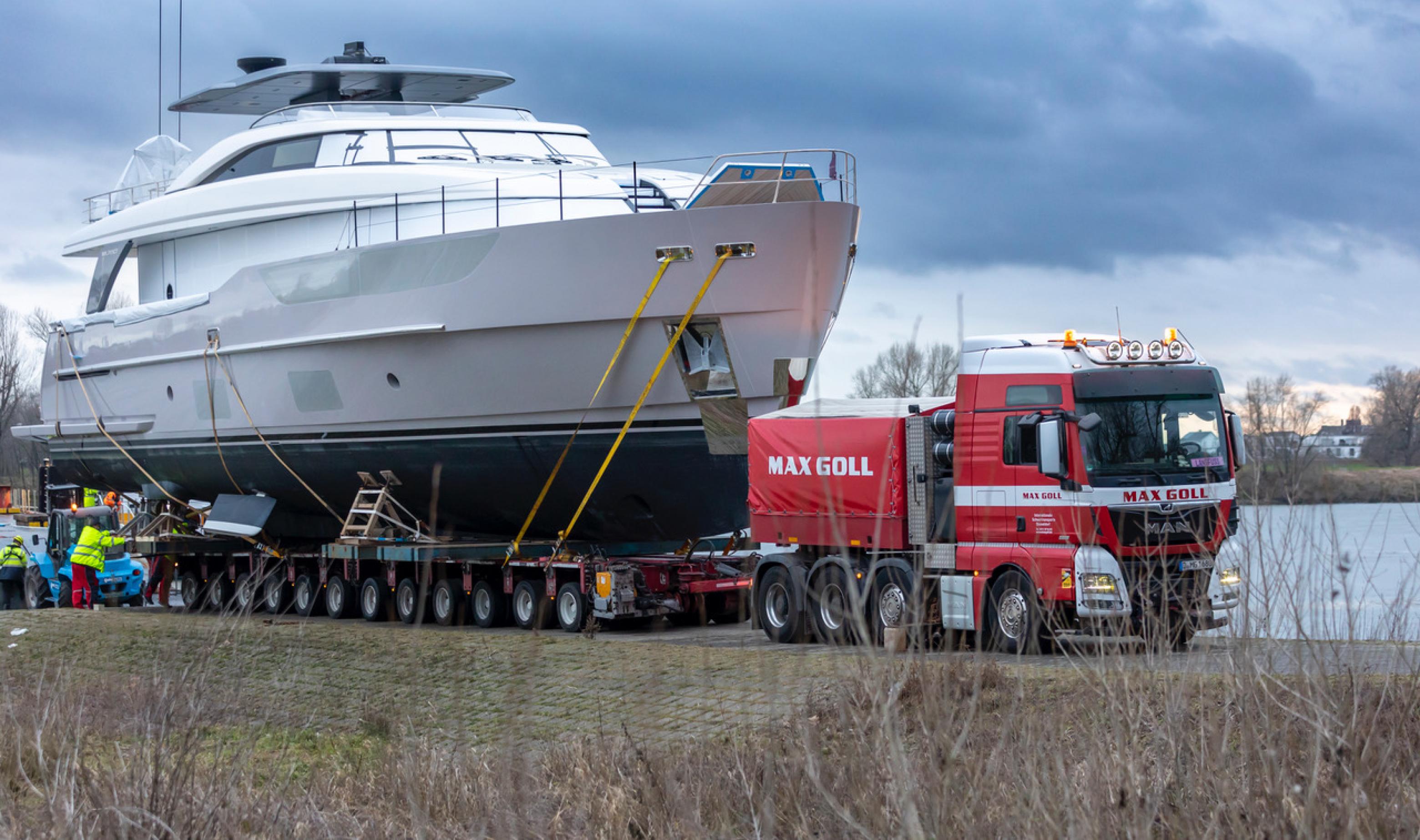 Weiße Superyacht wird auf einem Lkw-Anhänger zur Messe transportiert