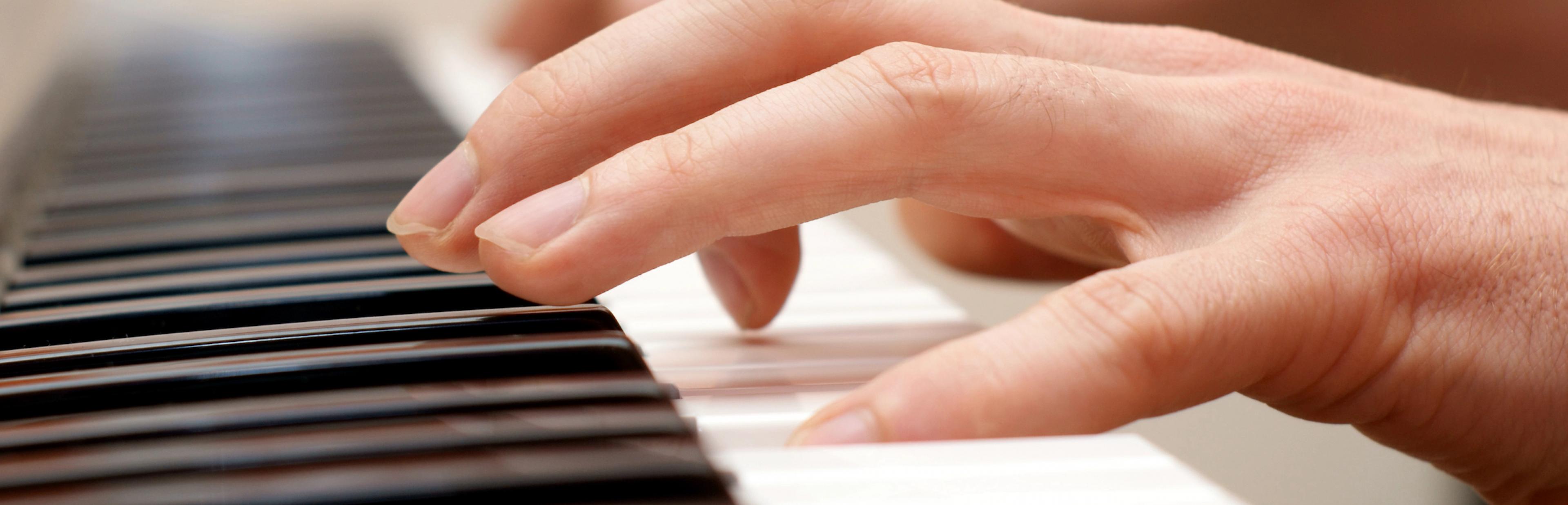 Hände eines Klavierspielenden auf den weißen und schwarzen Tasten.