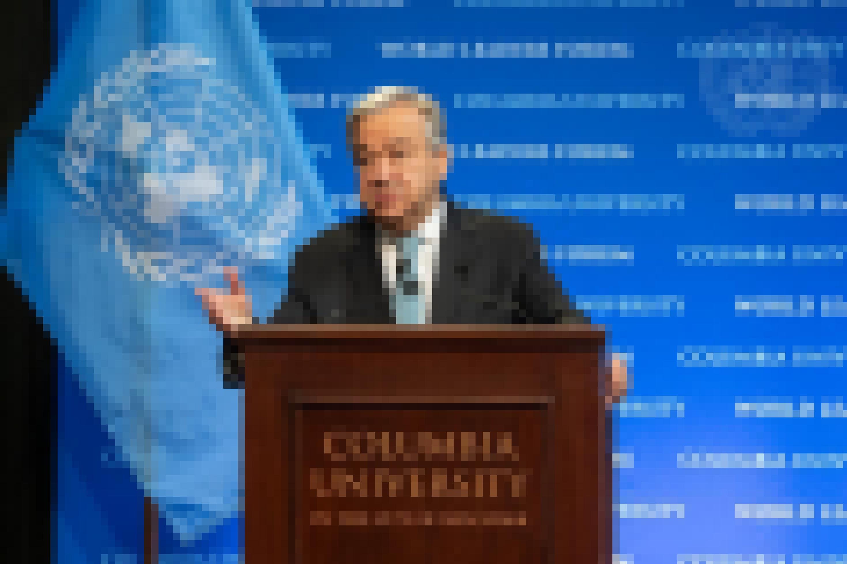 Guterres vor einer hellblauen UN-Flagge an einem Rednerpult mit der Aufschrift „Columbia University“.