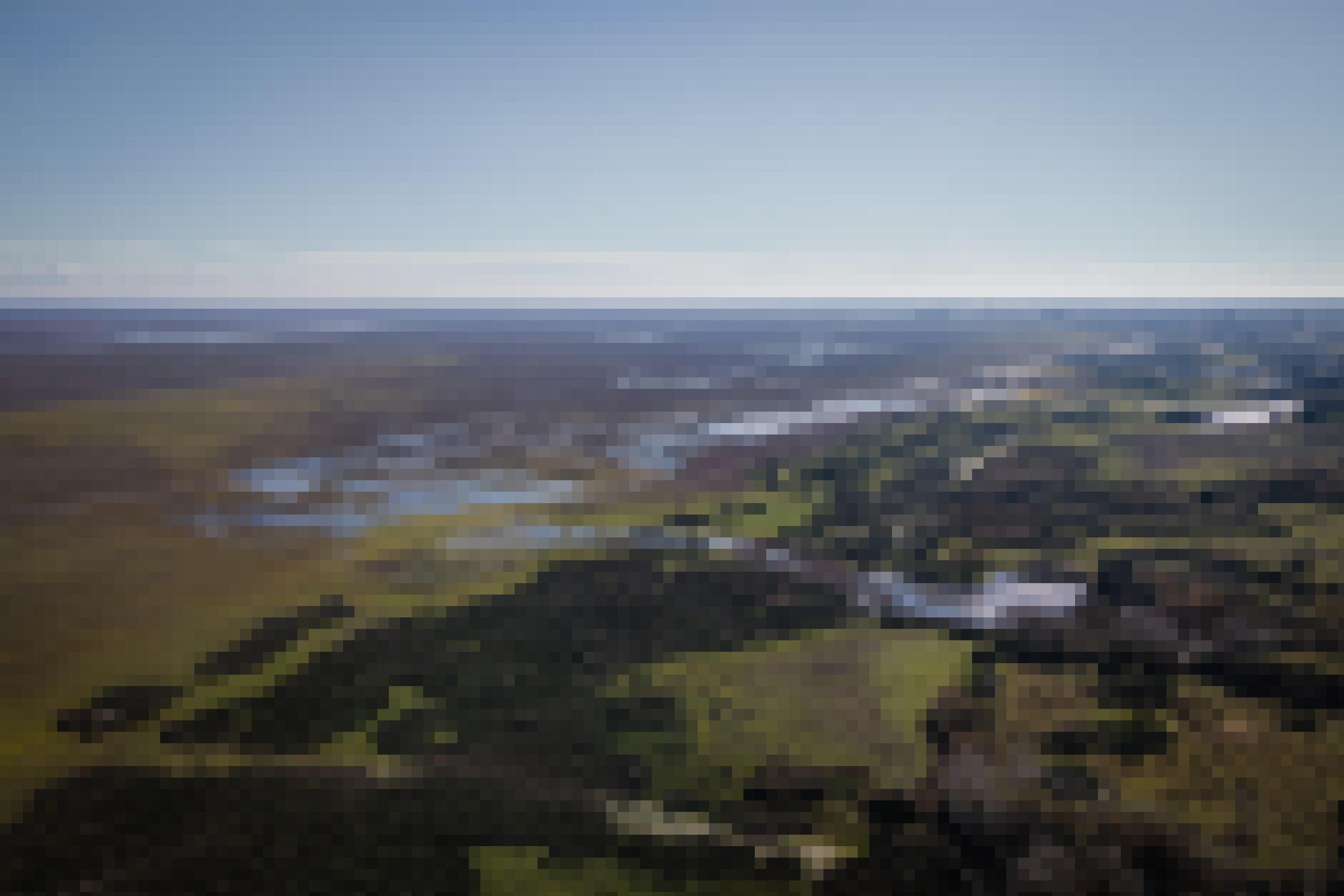 Blick von oben auf weite Landschaft mit Tümpeln und Trockenflächen.