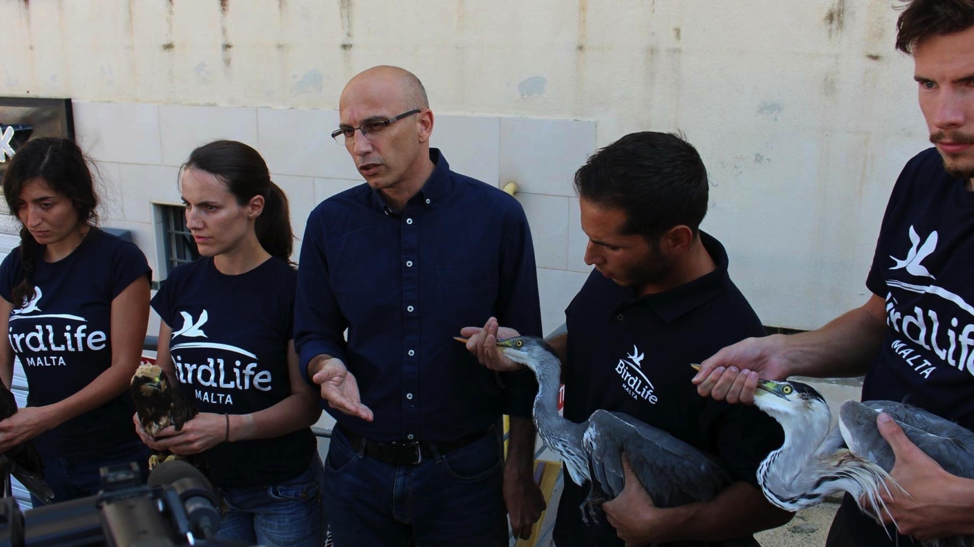 Eine Gruppe Menschen mit verletzten Vögeln in der Hand. Viele tragen ein T-Shirt mit der Aufschrift „BirdLife Malta“