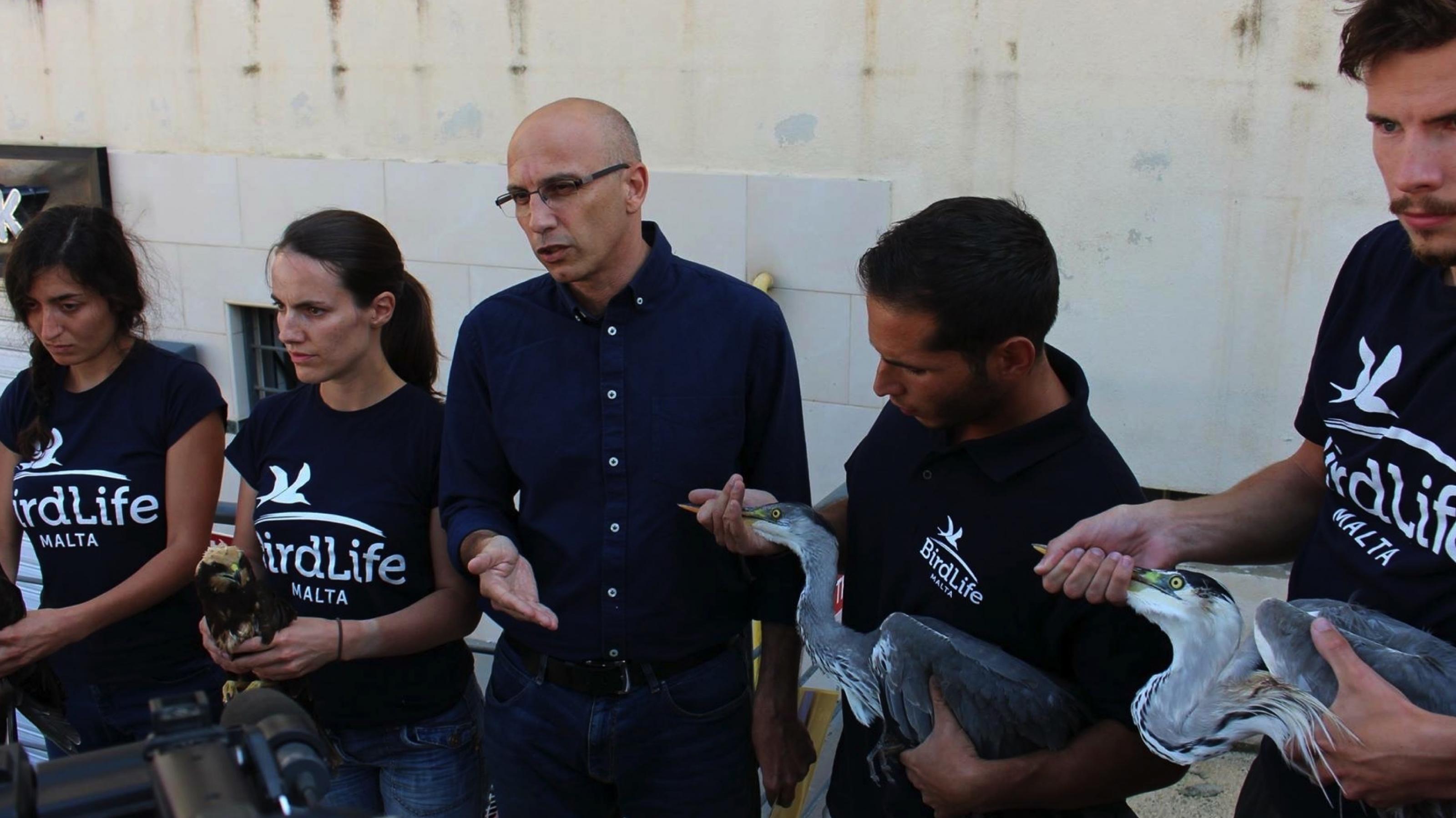 Eine Gruppe Menschen mit verletzten Vögeln in der Hand. Viele tragen ein T-Shirt mit der Aufschrift "BirdLife Malta"