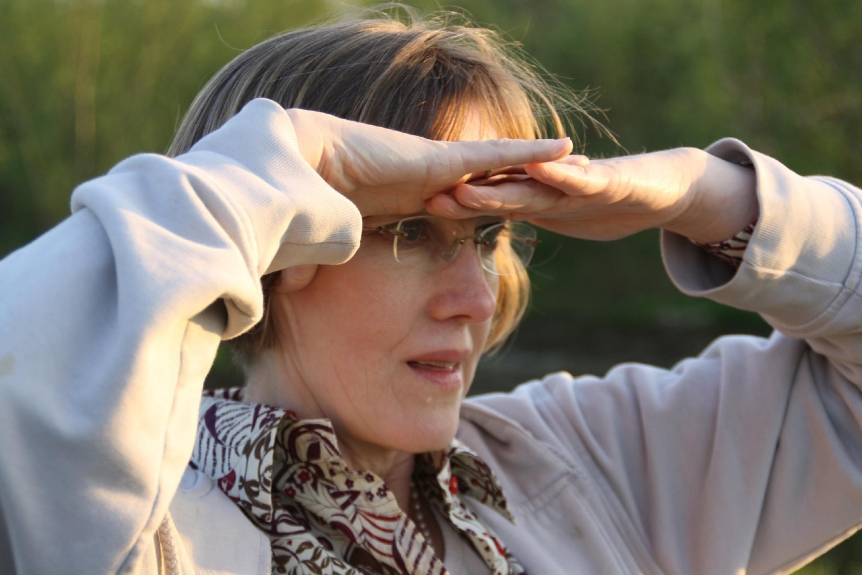 Foto von Johanna Romberg. Sie schützt ihre Augen mit ihren Händen vor der Sonne.