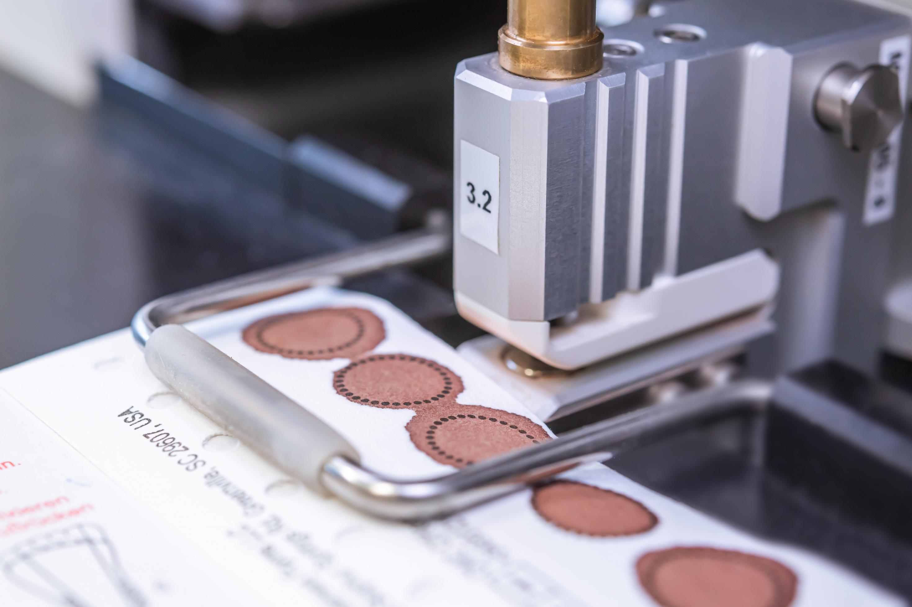 Das Neugeborenenscreening mit Trockenblut von Babys wird überwiegend von Maschinen geleistet, damit es schnell und fehlerfrei erfolgen kann. Hier stanzt eine Maschine ein Stück aus einem Filterpapier.