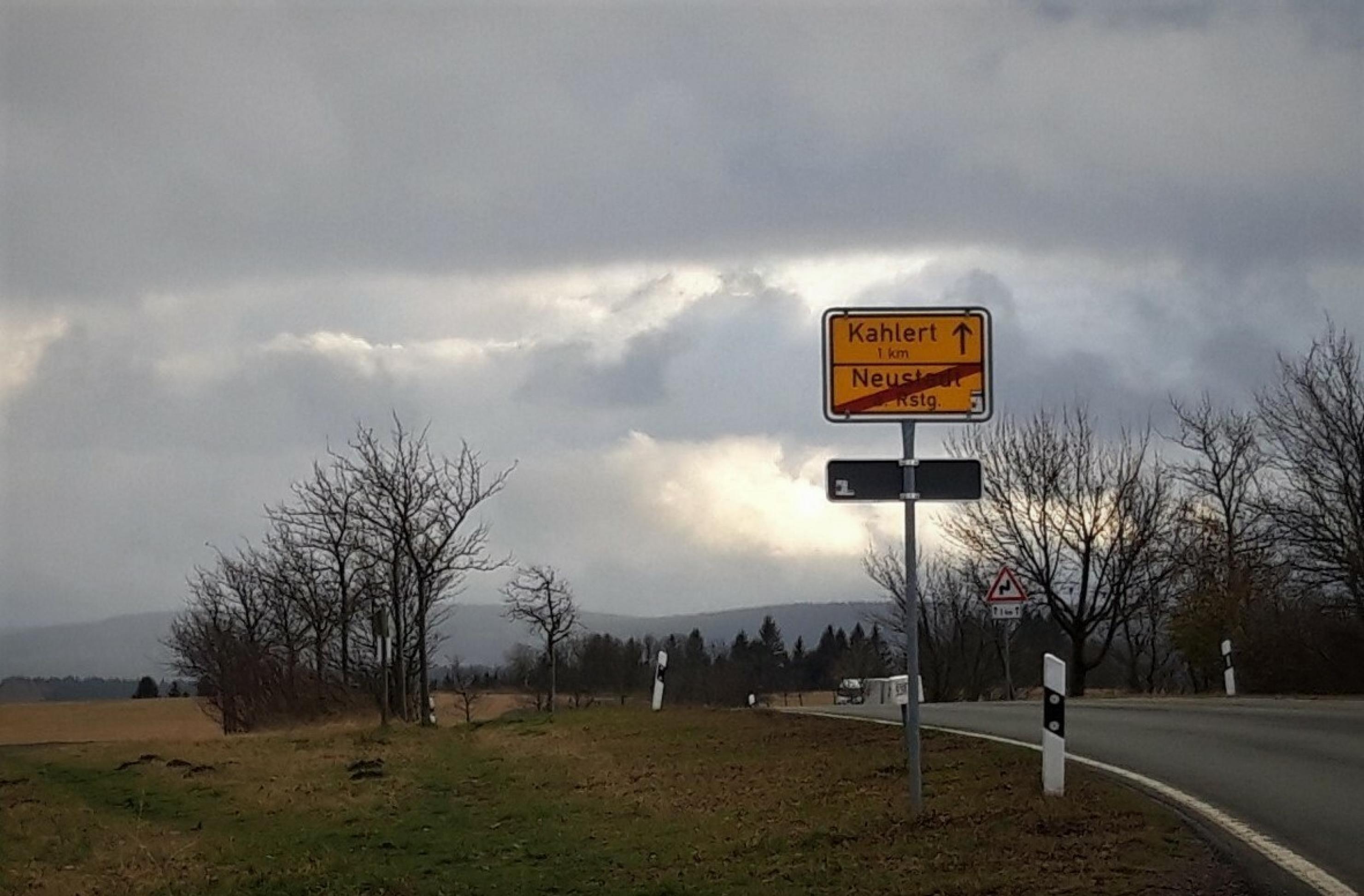 Am Ortsausgang von Neustadt am Rennsteig kündigt zwischen kahlem Geäst das Ortsschild an: Bis Kahlert ein Kilometer.