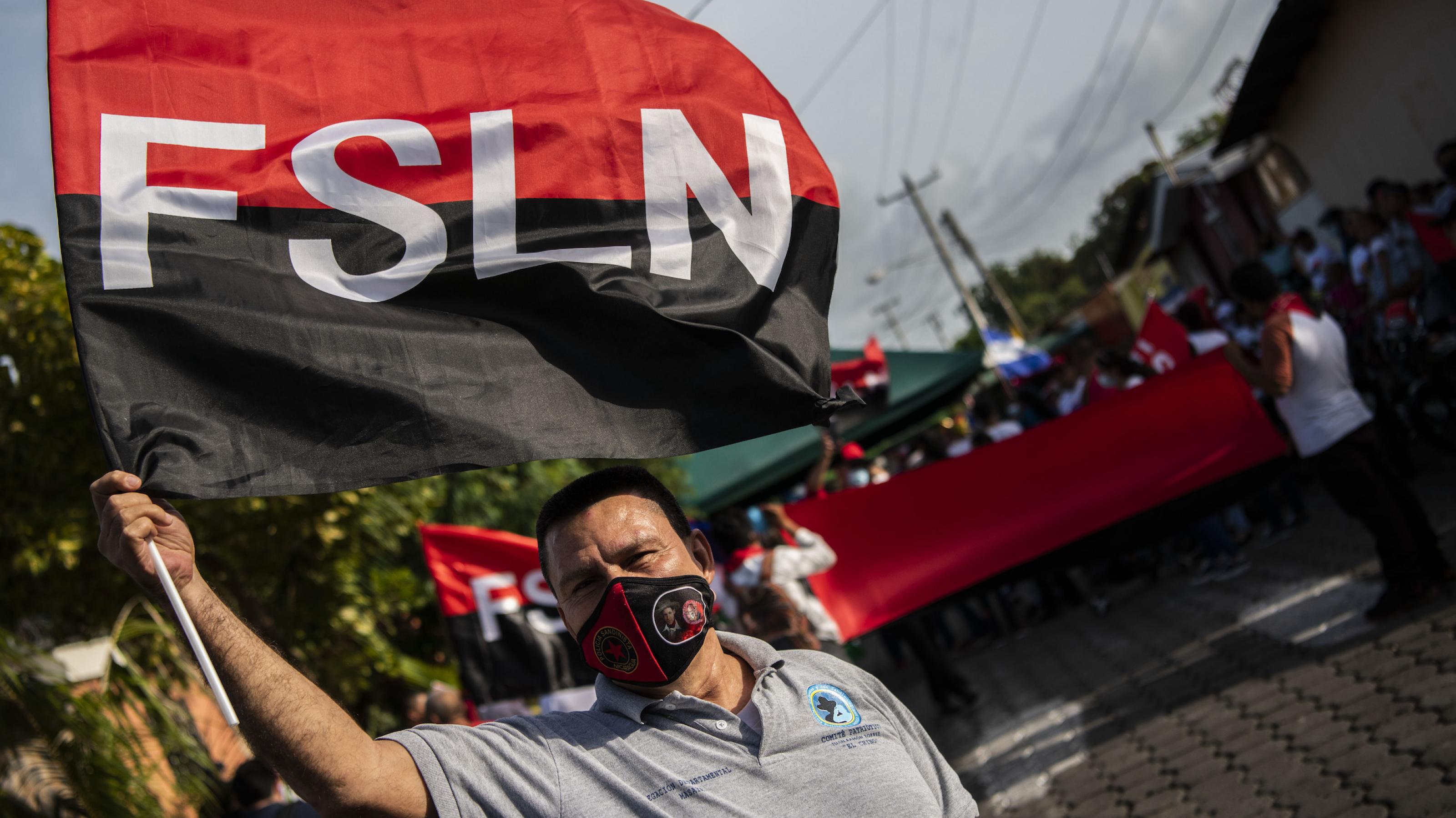 Ein Mann schwenkt eine Flagge der Sandinistischen Nationalen Befreiungsfront (FSLN). Im Hintergrund sind weitere Demonstranten zu sehen.