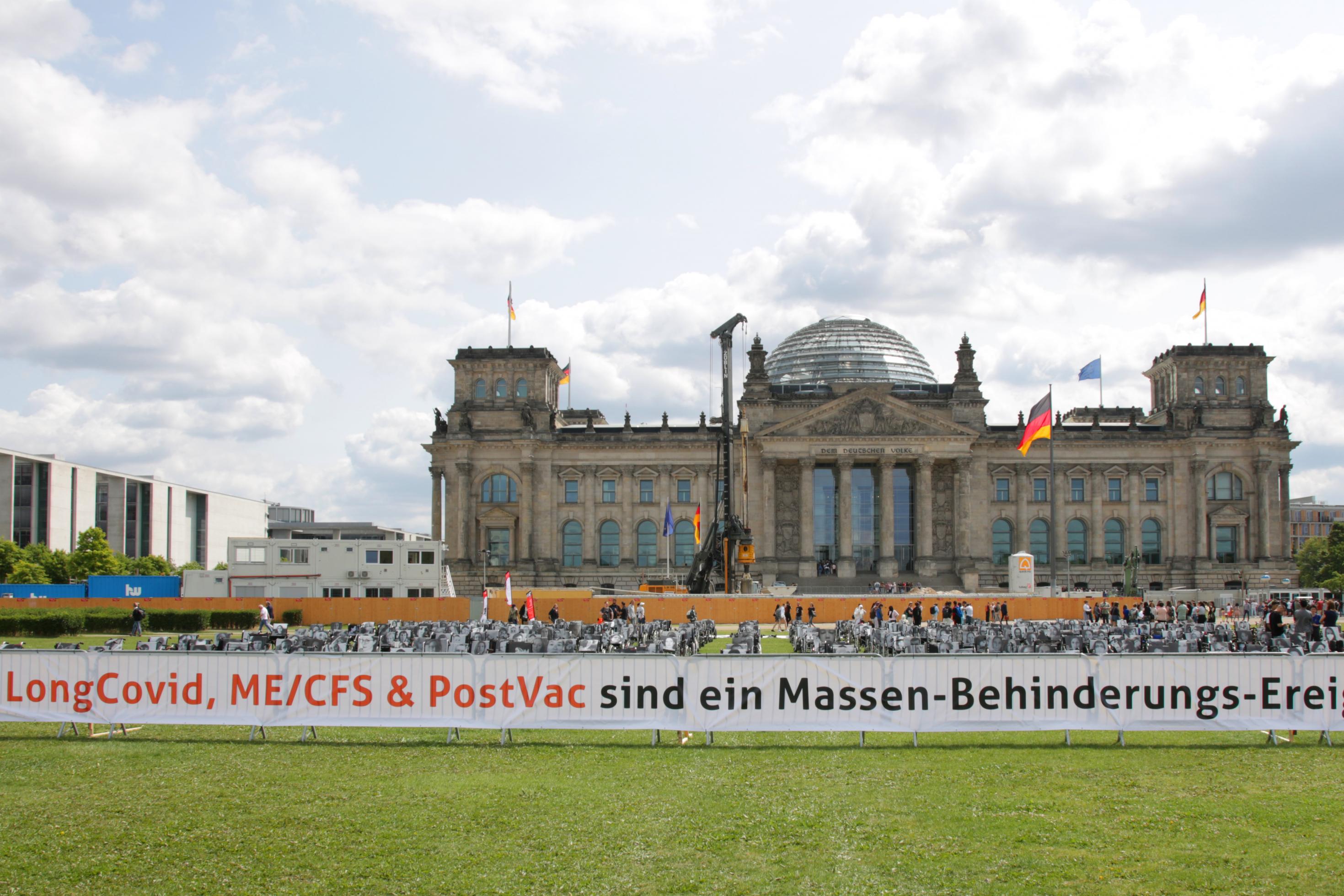 Protest für eine bessere Versorgung: Die Initiative präsentiert ein breites Banner vor dem Reichstagsgebäude, die Aufschrift: „Long-COVID, ME/CFS & Post Vac sind ein Massen-Behinderungs-Ereignis“. Foto vom 4. Juli 2023.