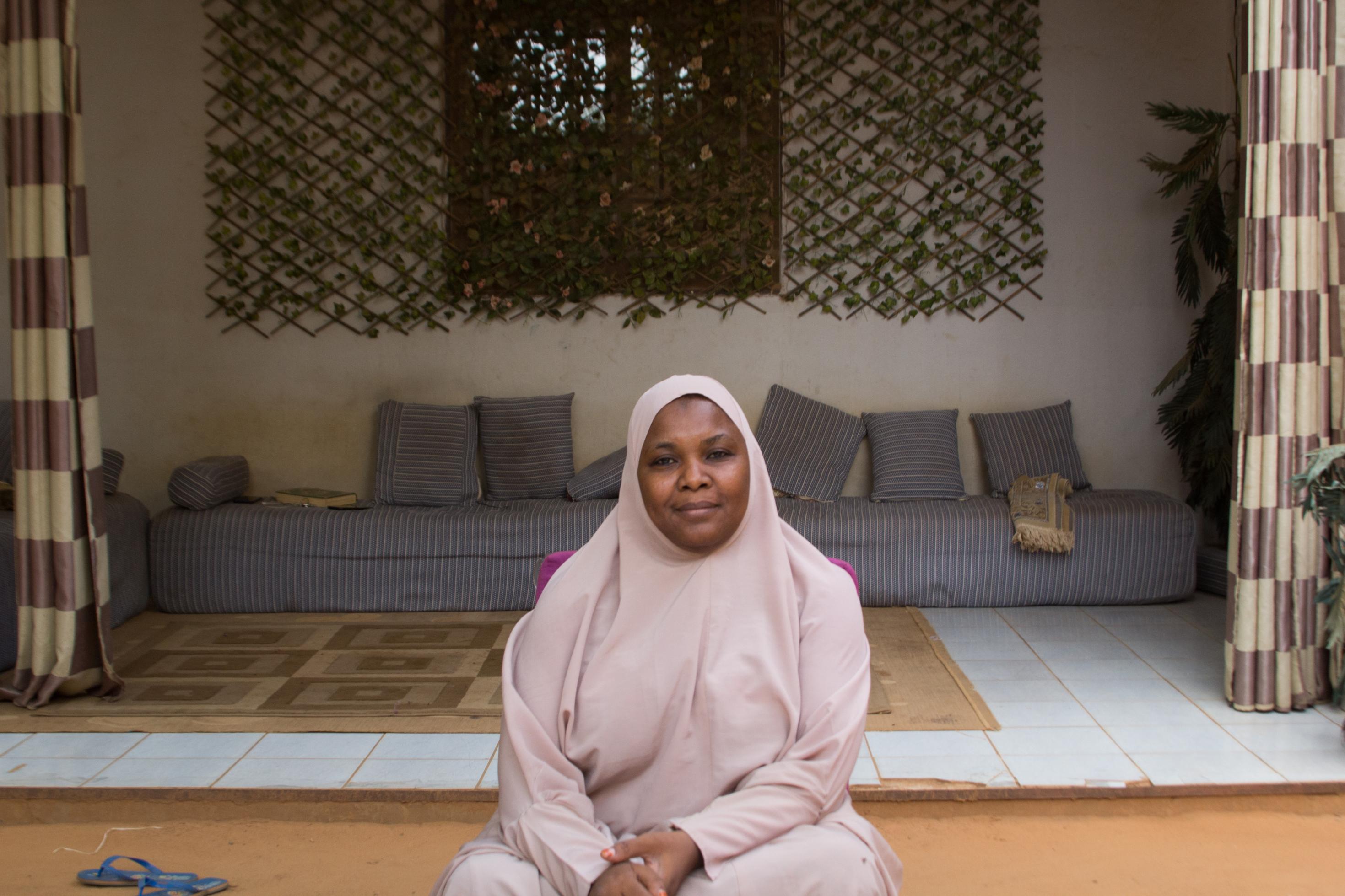 Malama Sakına trägt einen rosafarbenen Ganzkörperschleier. Im Hintergrund die Sitzgelegenheiten auf der Veranda ihres Hauses.