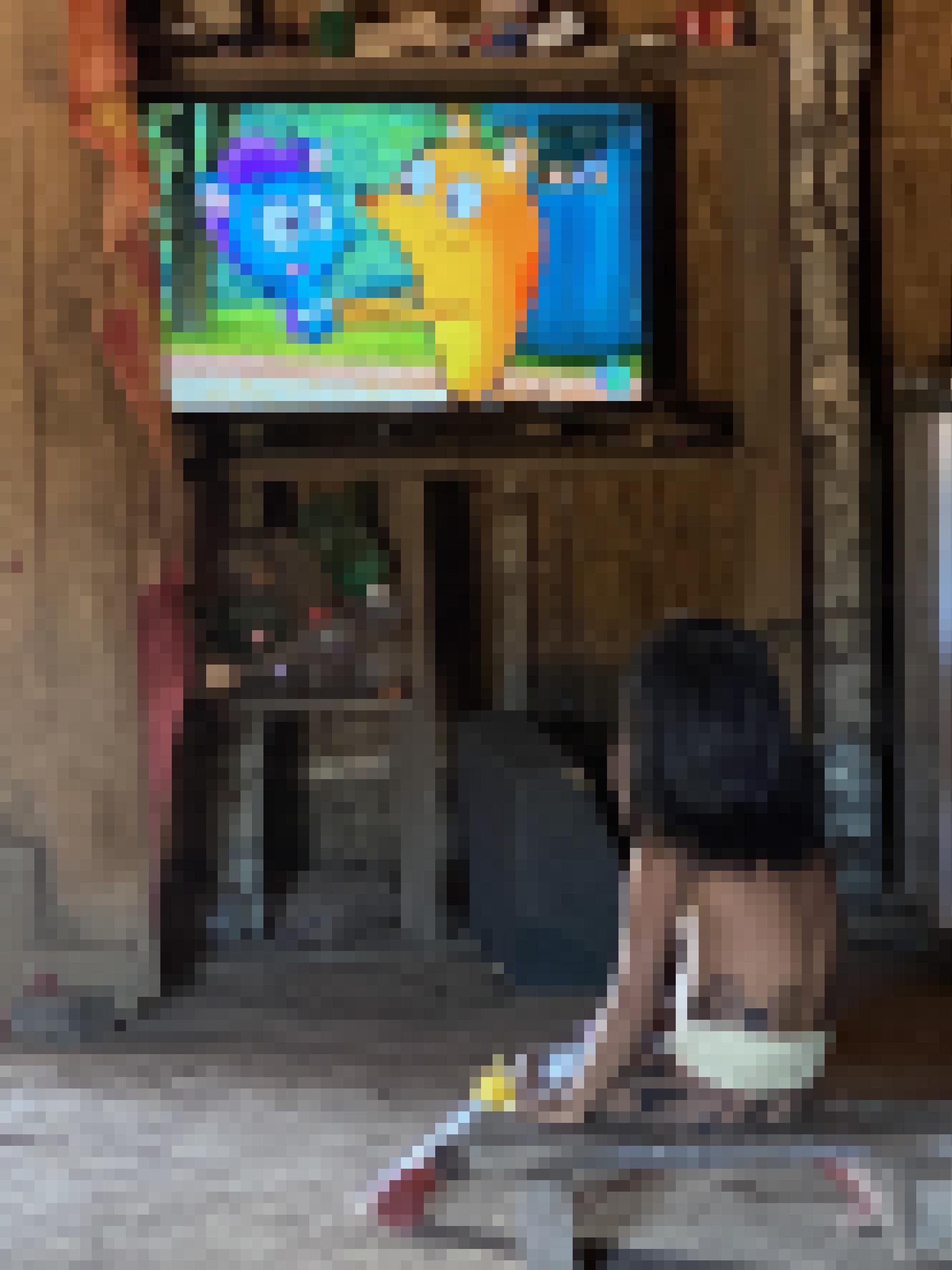 Ein bemaltes fünfjähriges Mädchen sitzt im dunklen Großhaus vor einem Flatscreen Fernseher und guckt eine Kindersendung.