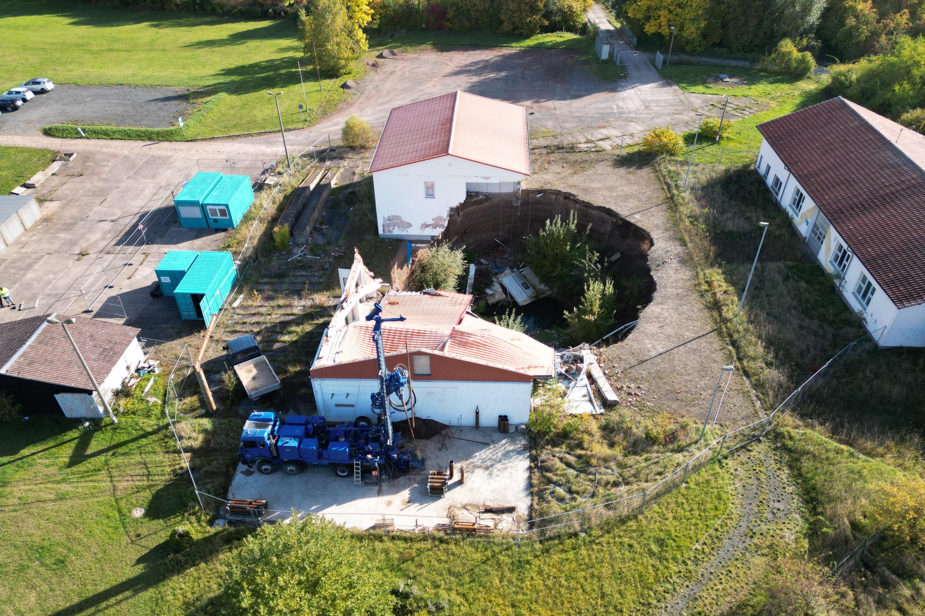 Luftbild eines Hauses, vor dem sich ein großes Loch im Erdreich auftut.