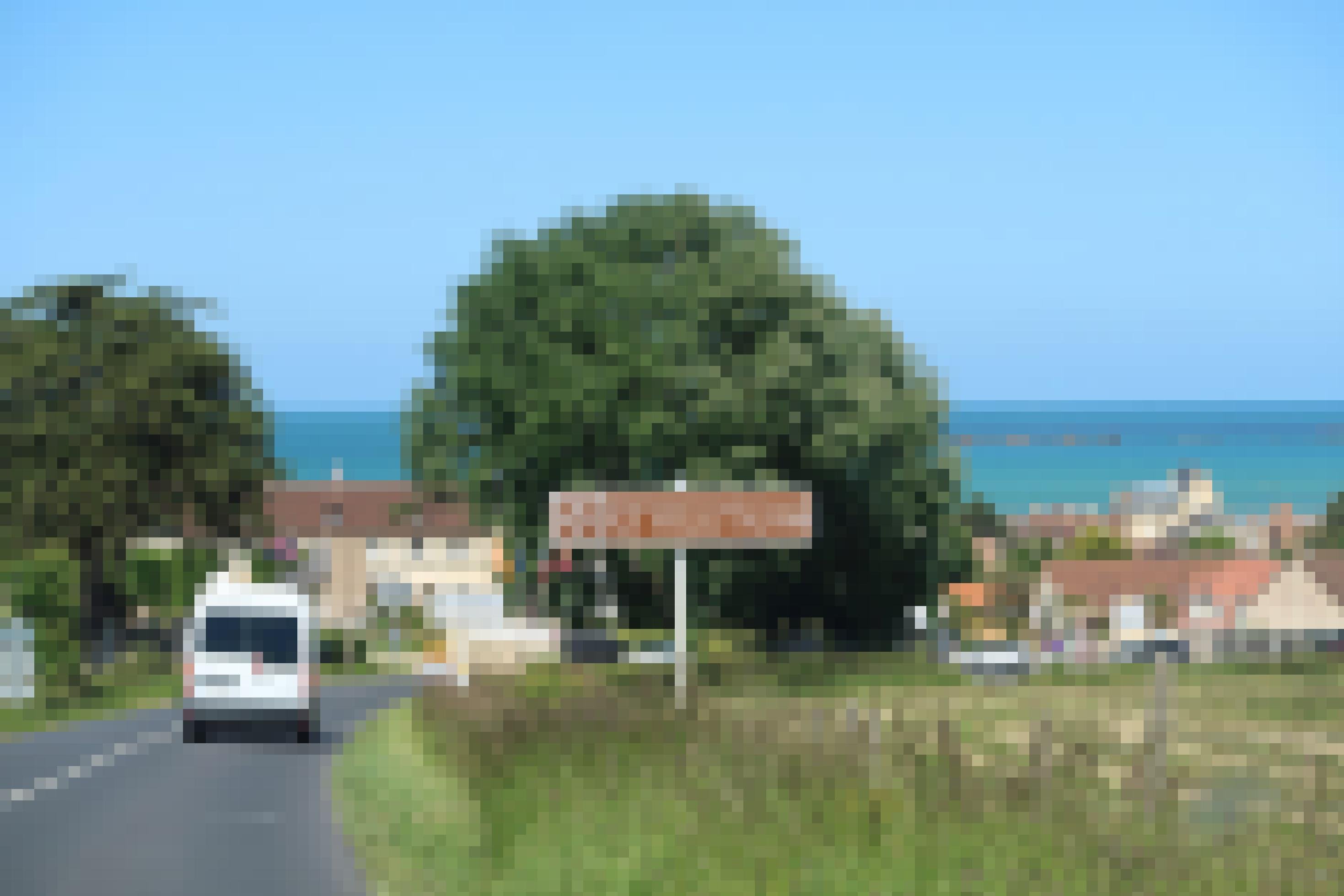 Ortseinfahrt in ein Dorf in der Normandie, im Hintergrund ist das Meer zu sehen