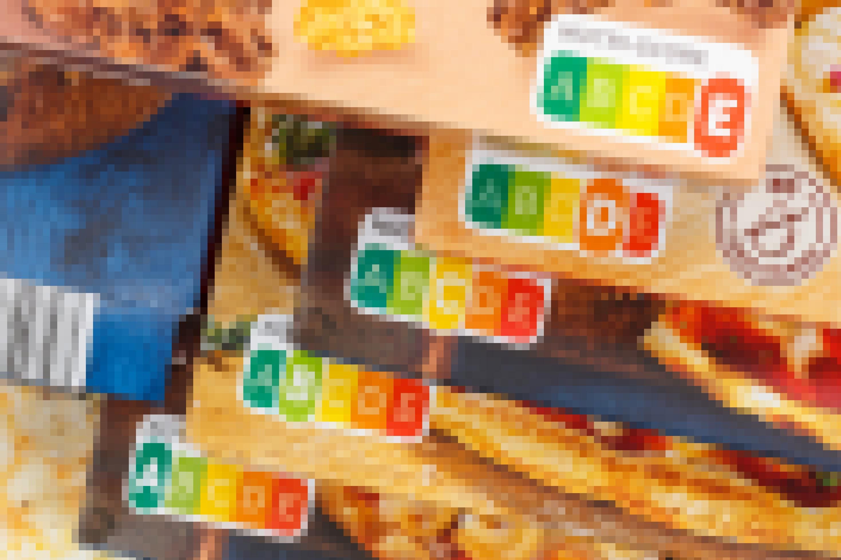 Das Bild zeigt Ecken mehrerer Lebensmittelpackungen. Neben einem kleinen Teil der Produktfotos von Pizza und Frühstücksflocken ist vor allem das Nutri-Score-Label zu sehen, die in Ampelfarben gestaltete Nährwertkennzeichnung.