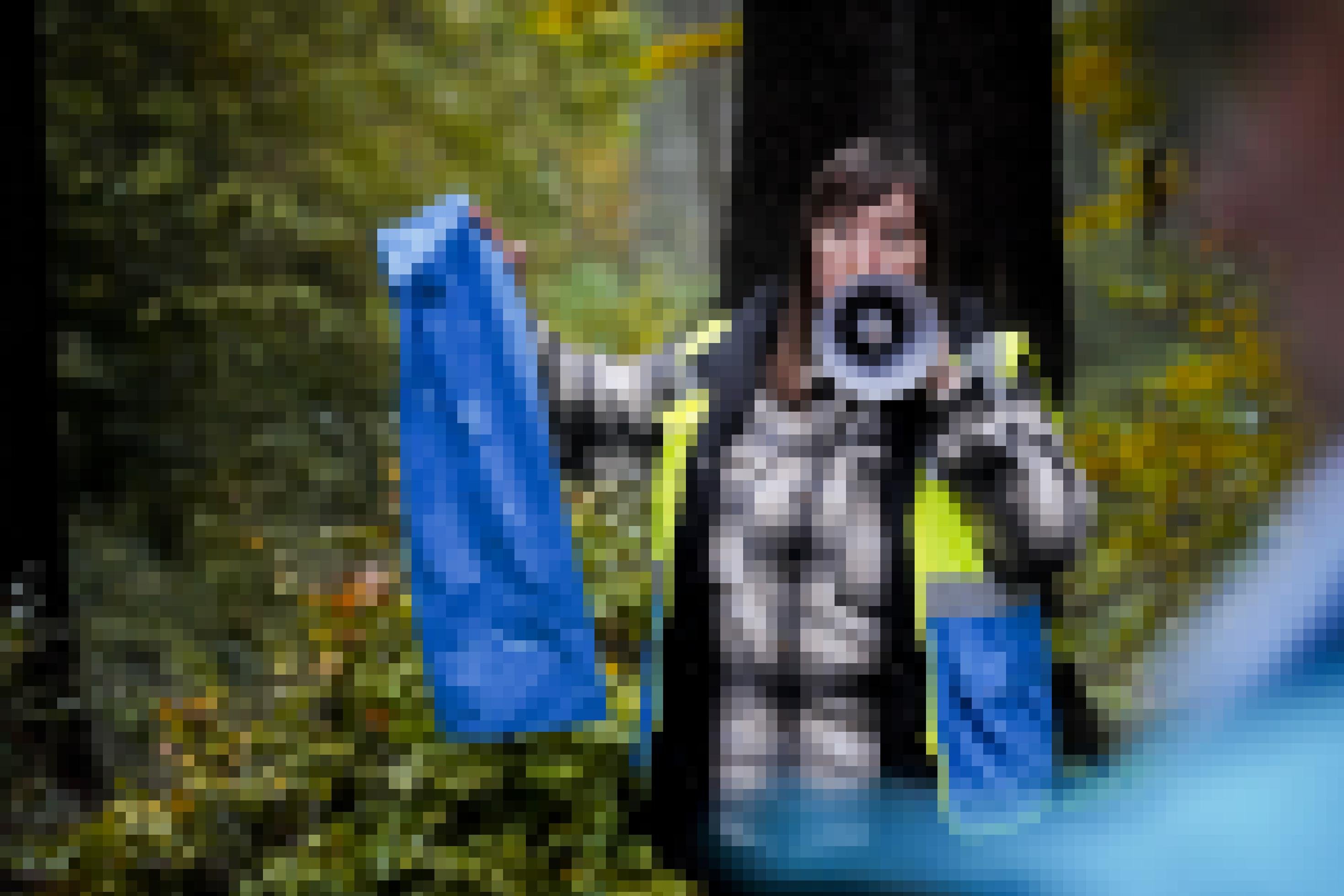Valeria Tsikava steht mit Megafon und Mülltüte im Wald.