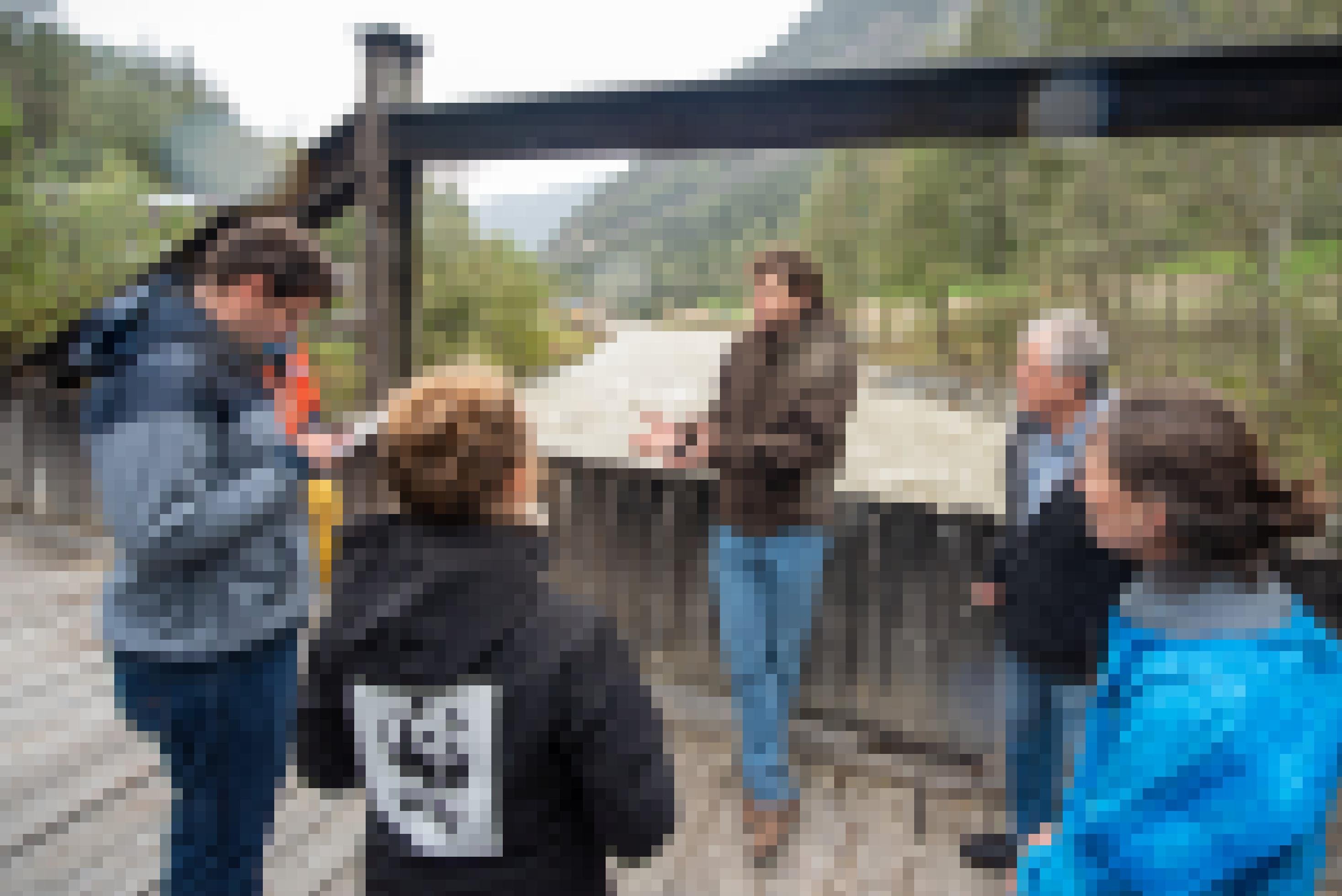 Menschen stehen auf einer Holzbrücke über einen reissenden Gebirgsbach und reden.