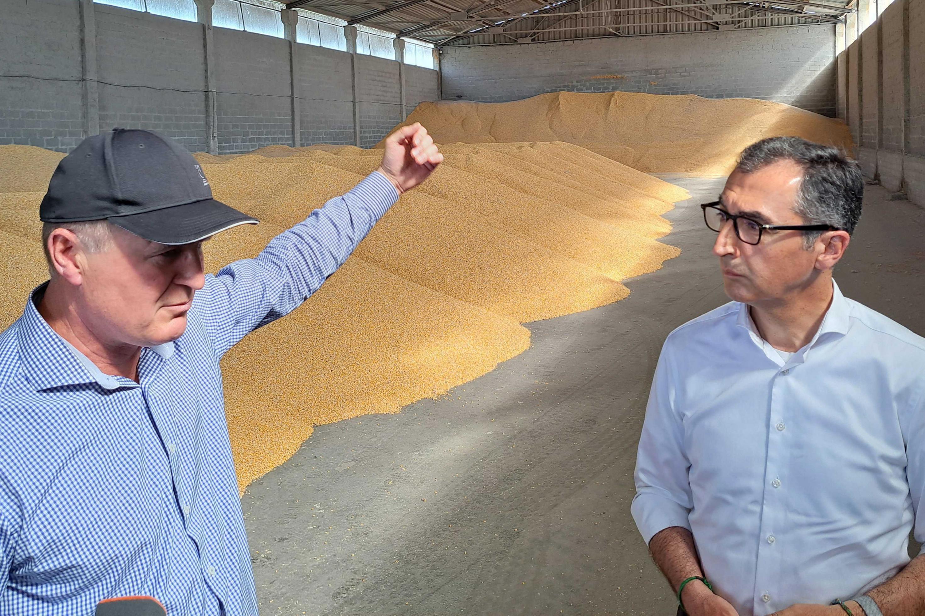 Cem Özdemir (r, Bündnis 90/Die Grünen), Bundesminister für Ernährung und Landwirtschaft, besichtigt mit Landwirt Viktor Scheremeta eine Halle in der Mais gelagert wird.
