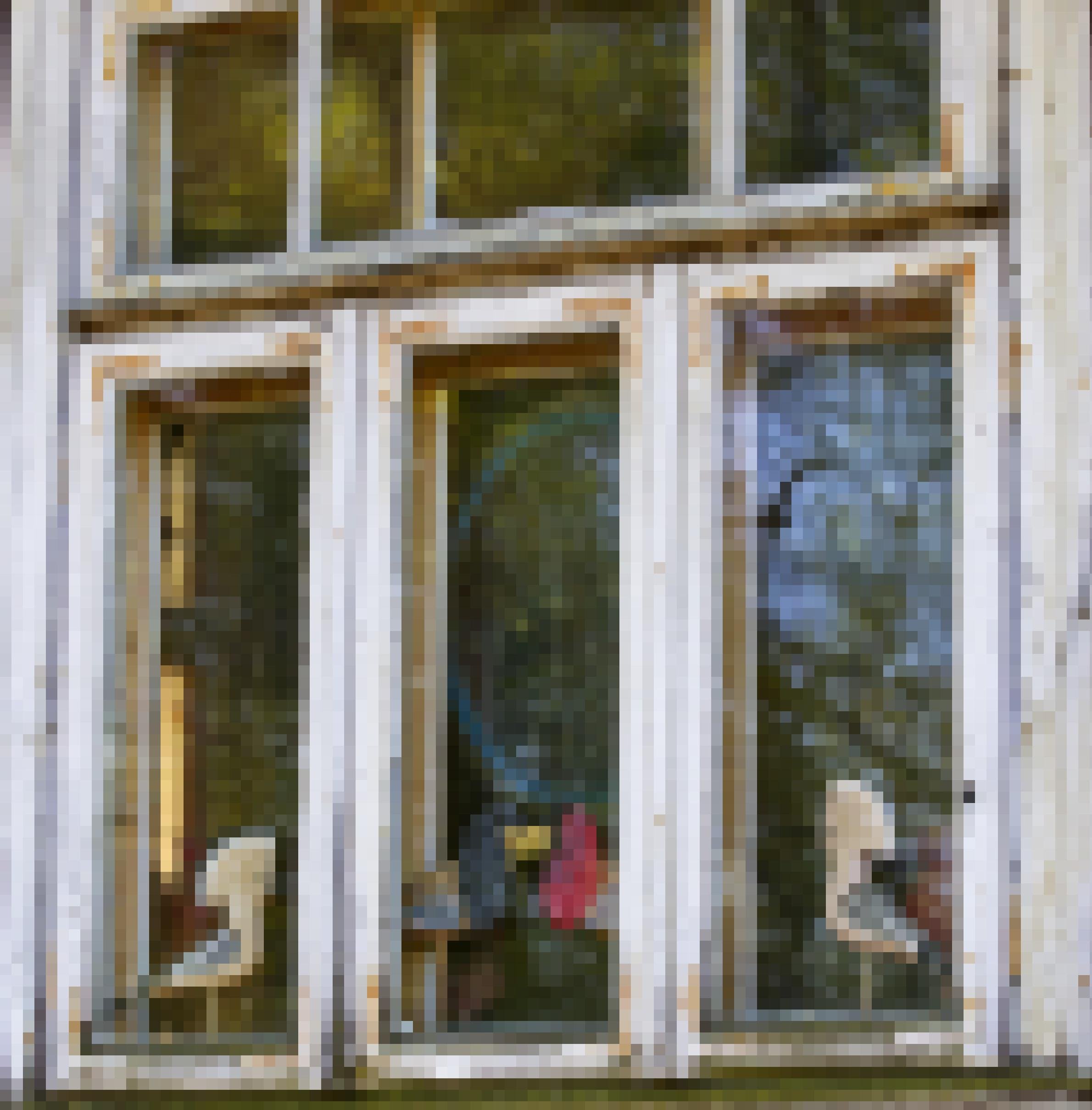 Ein altes Holzfenster, im Inneren sind Holzfiguren von Vögeln – zwei Wiedehopfe und Kampfläufer – sichtbar.