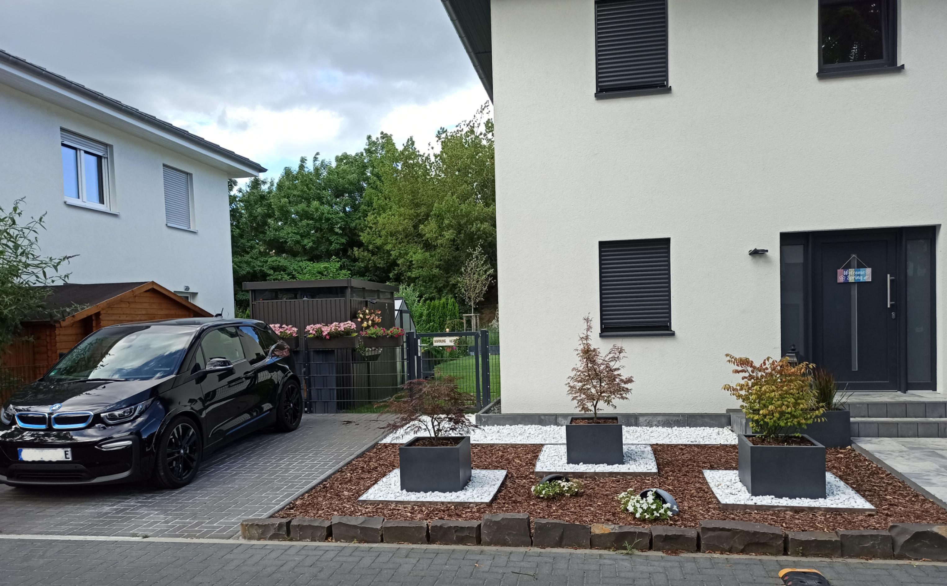 Ein Elektroauto steht vor einem Haus mit Steingarten